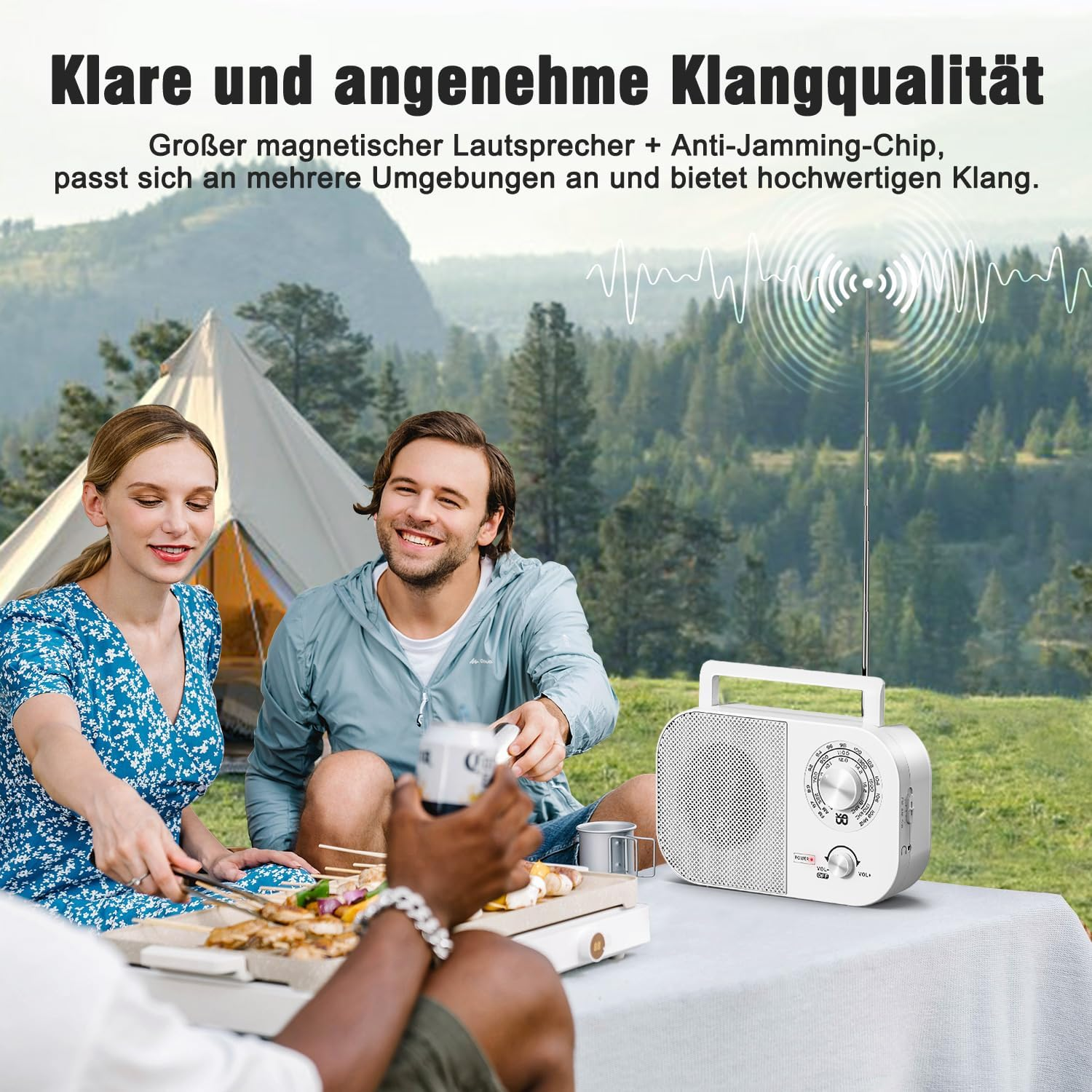 Leute um einen Tisch mit Essen. Ein Radio steht auf dem Tisch. Im Hintergrund ist ein Zelt zu sehen, was auf Camping hindeutet.