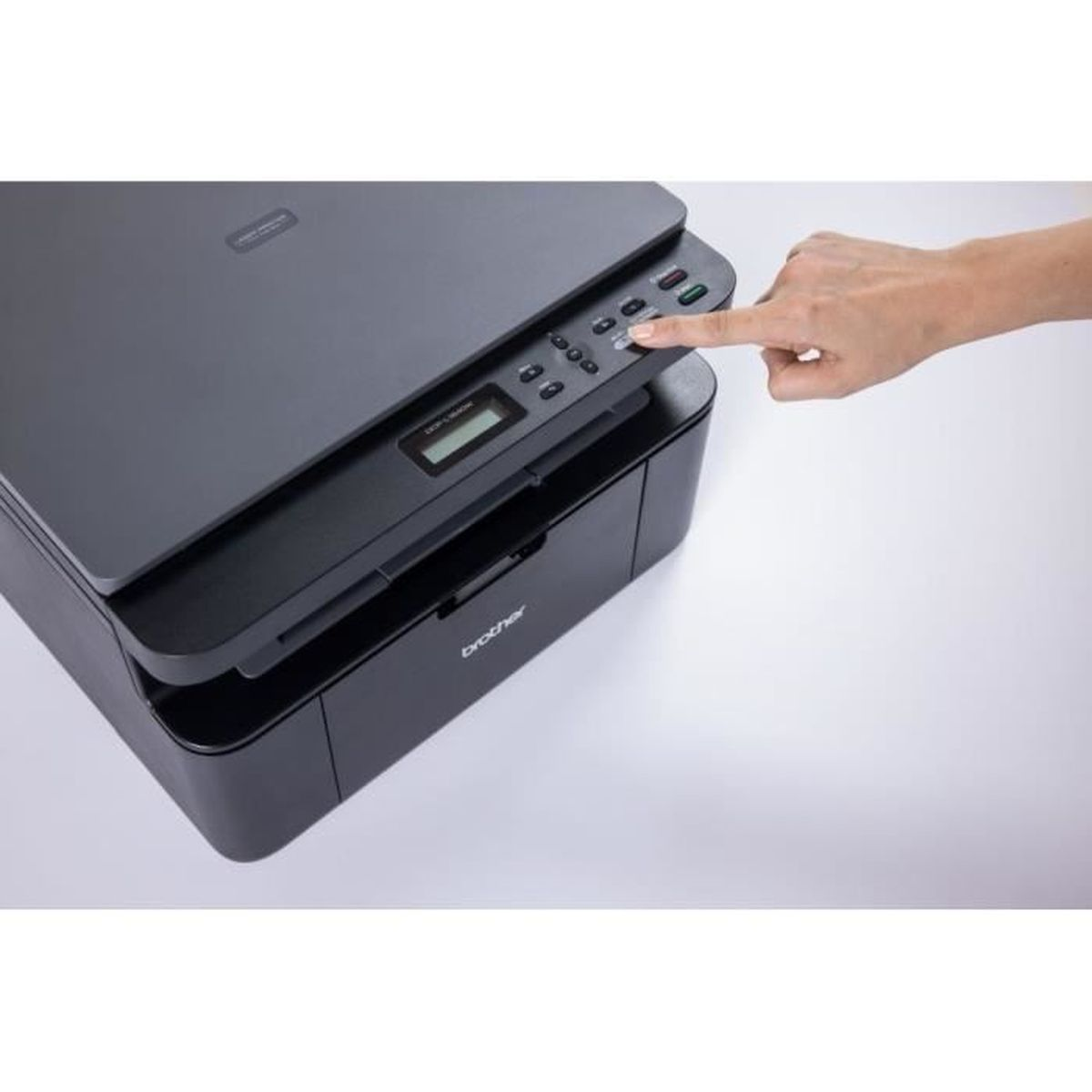 Een zwarte Brother-printer met een hand die op een knop drukt. De printer staat op een wit oppervlak.