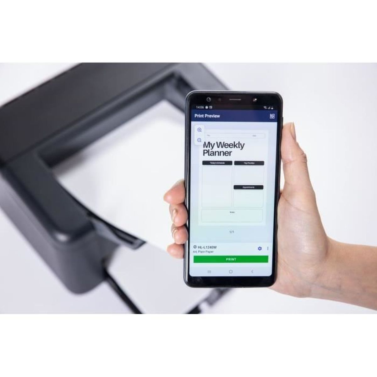 Ręka trzyma telefon z podglądem wydruku tygodniowego planera. W tle drukarka z kartką papieru.