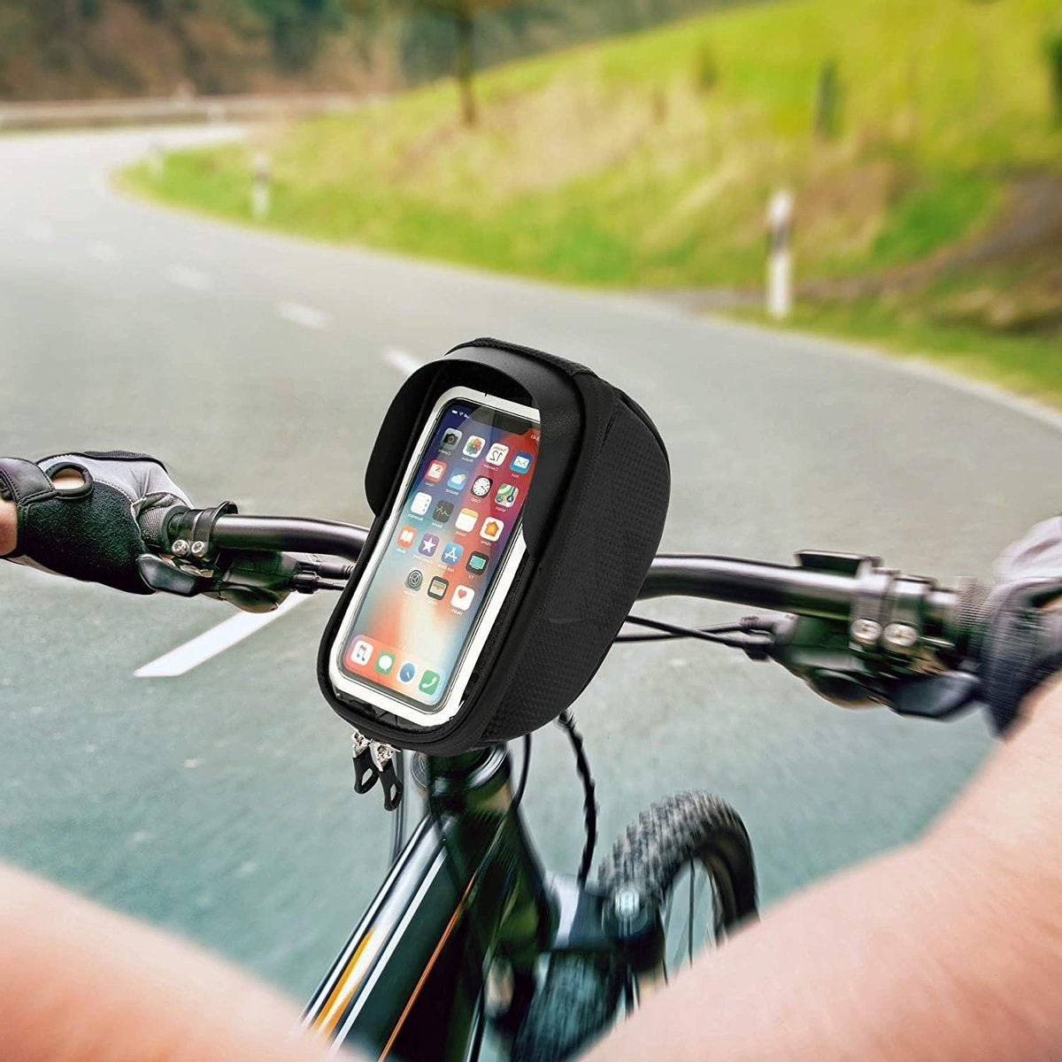 A cyclist's view, showcasing a phone in a black case on handlebars. Green foliage and road in the background.