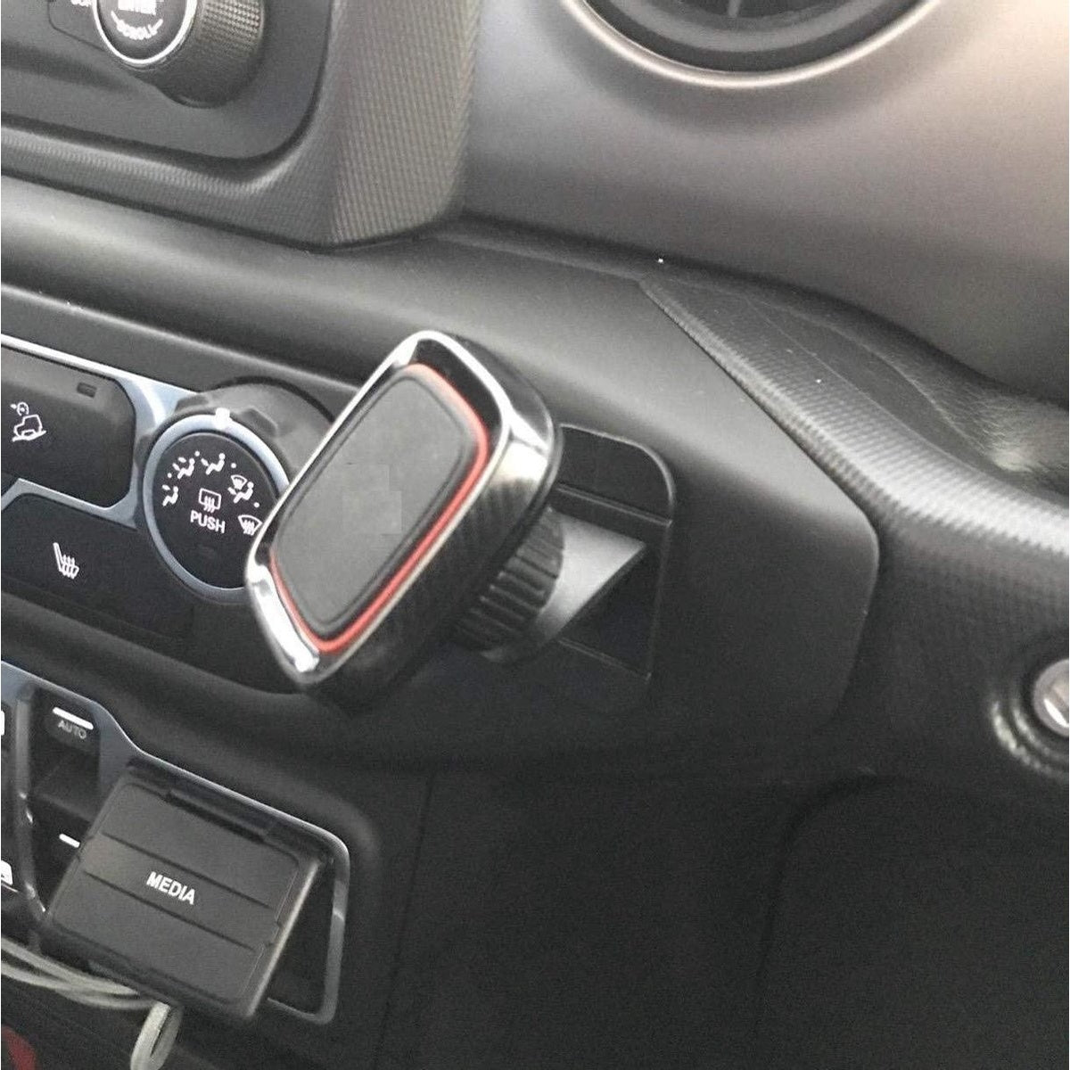 Het dashboard van een auto toont een telefoonhouder, klimaatregelaars en een mediasleuf. De houder is zwart en rood, schuin naar de bestuurder.