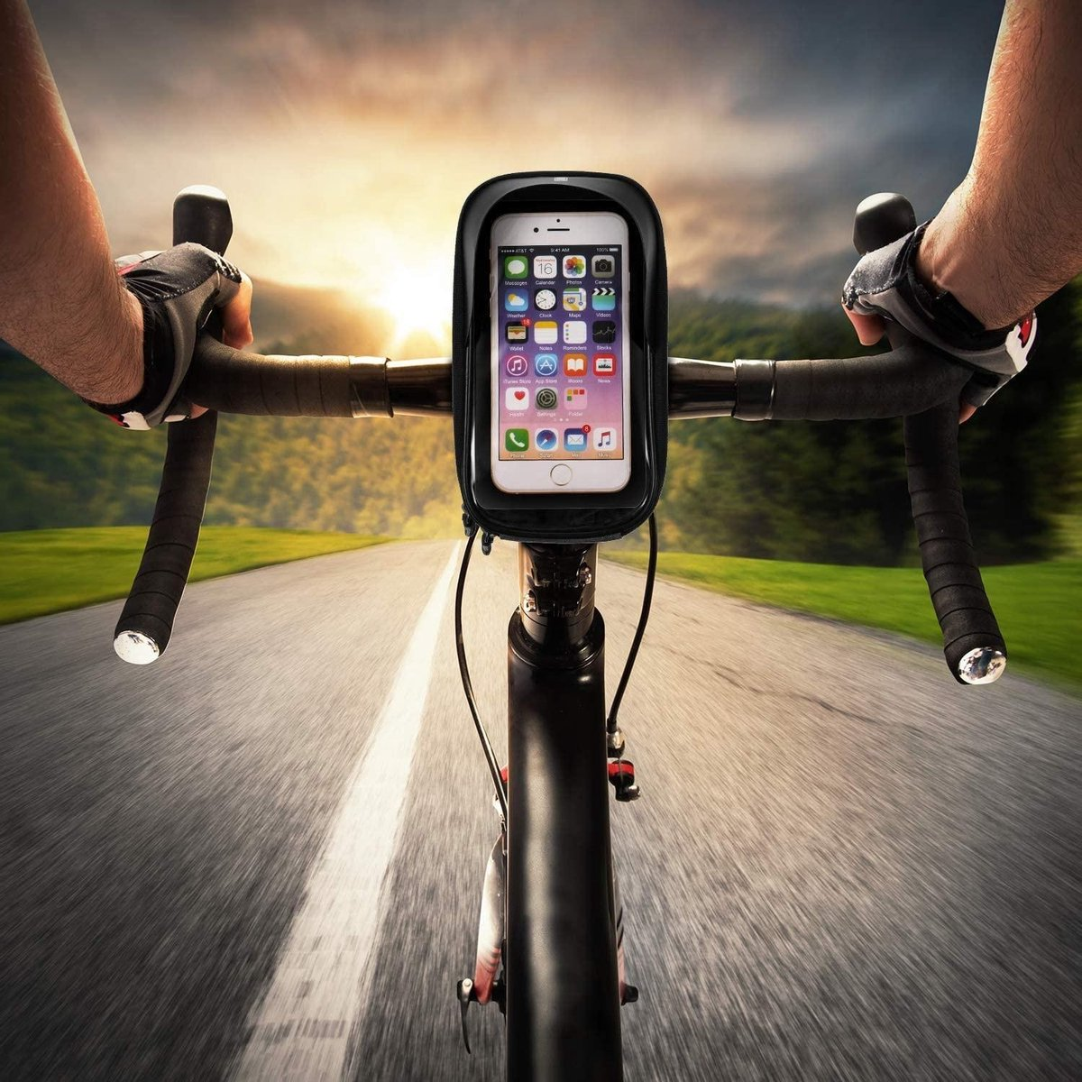 POV van de fietser op een fiets, telefoonhouder op het stuur. Telefoon toont apps. Asfaltweg strekt zich uit, bomen aan de zijkanten, zonsondergang op de achtergrond.