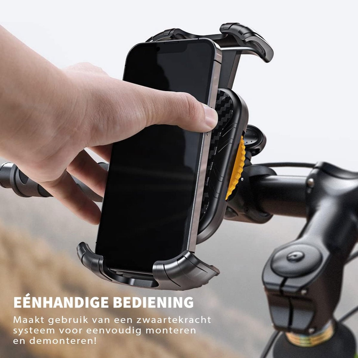 A hand holding a smartphone in a black phone holder attached to a bicycle handlebar. The phone screen is black.
