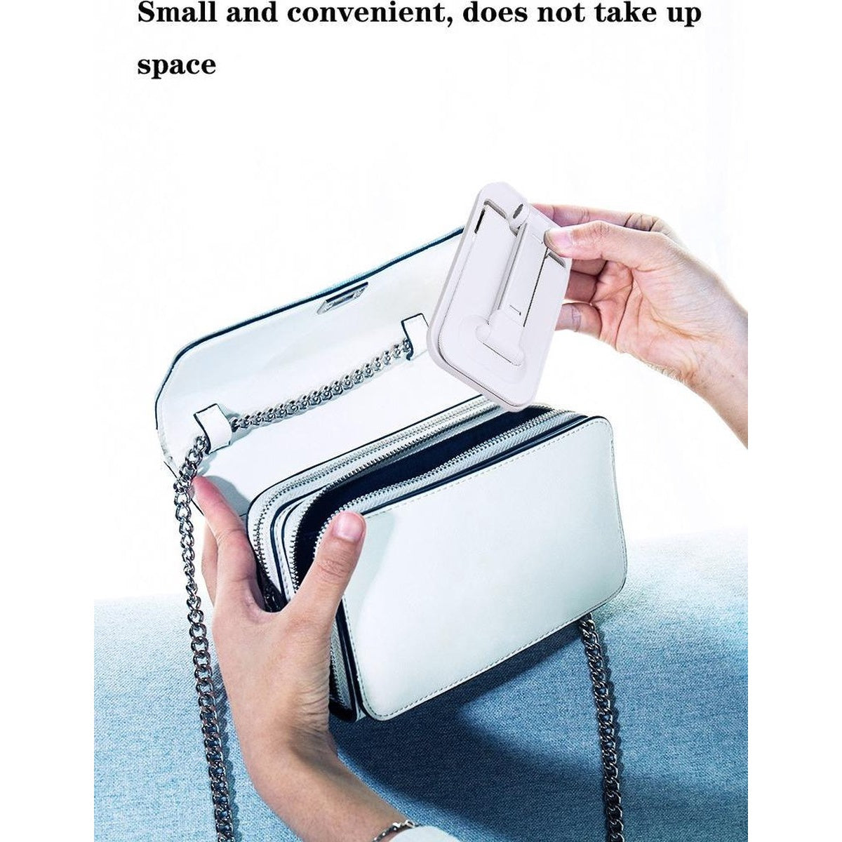 Een persoon houdt een witte telefoonstandaard vast, naast een witte tas met een ketting. De tas is open.