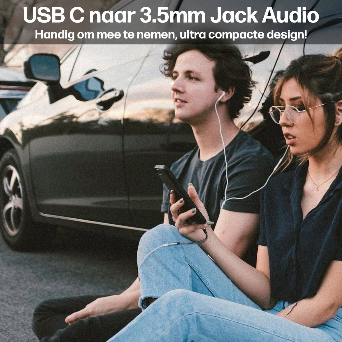 Twee mensen zitten bij een auto en luisteren muziek met bedrade oortelefoons. Eén persoon houdt een telefoon vast die is aangesloten op een USB-C naar 3,5 mm jack adapter.