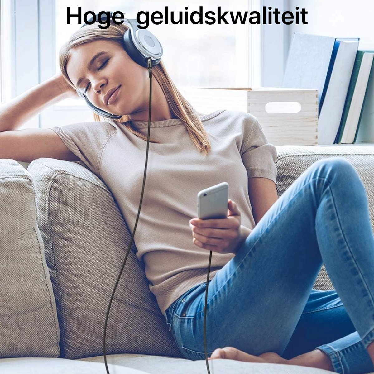 Woman with headphones and phone on a couch. She is listening to music. Background has books and a window.