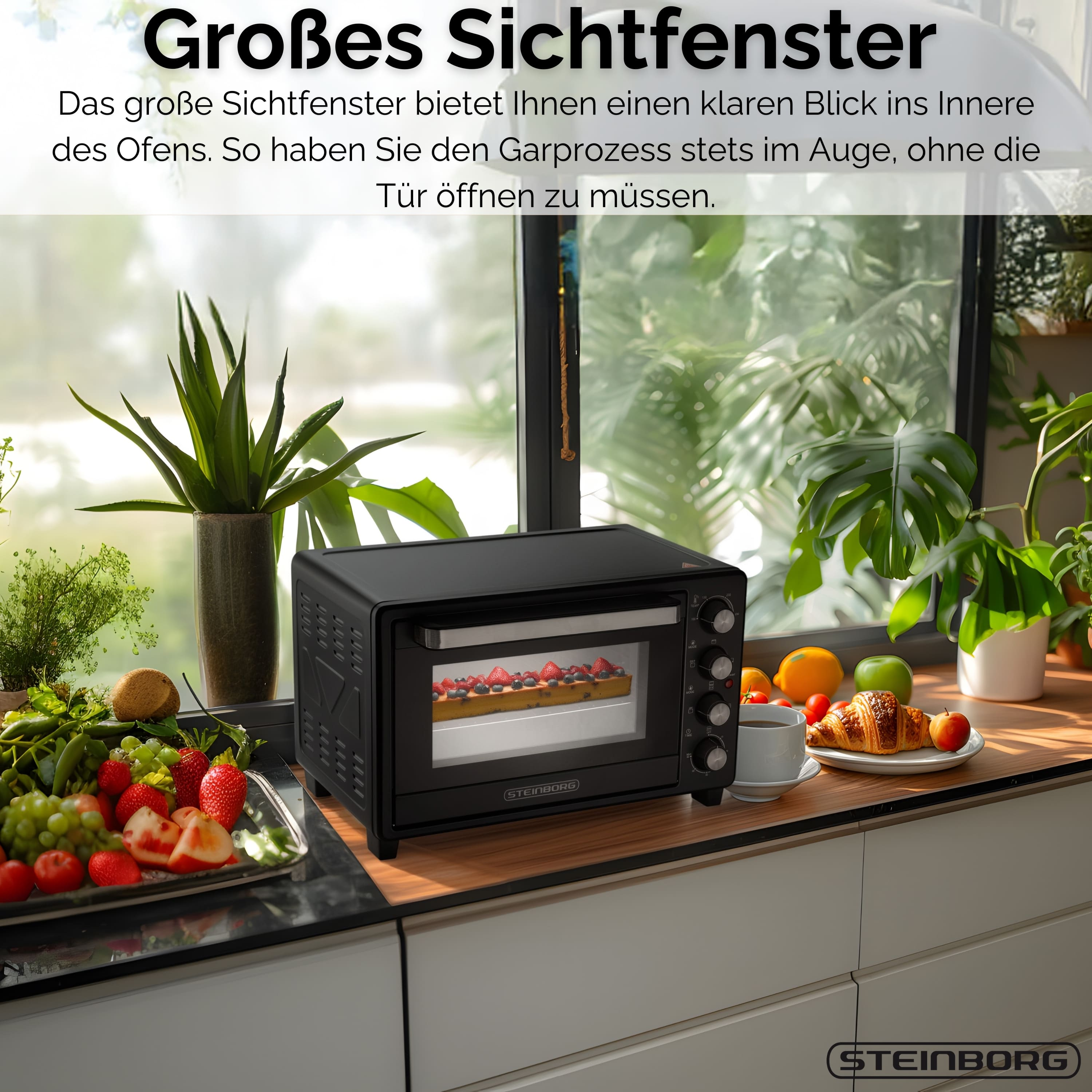 Schwarzer Ofen mit Glastür, Essen darin. Früchte, Pflanzen und ein Croissant stehen auf der Theke.