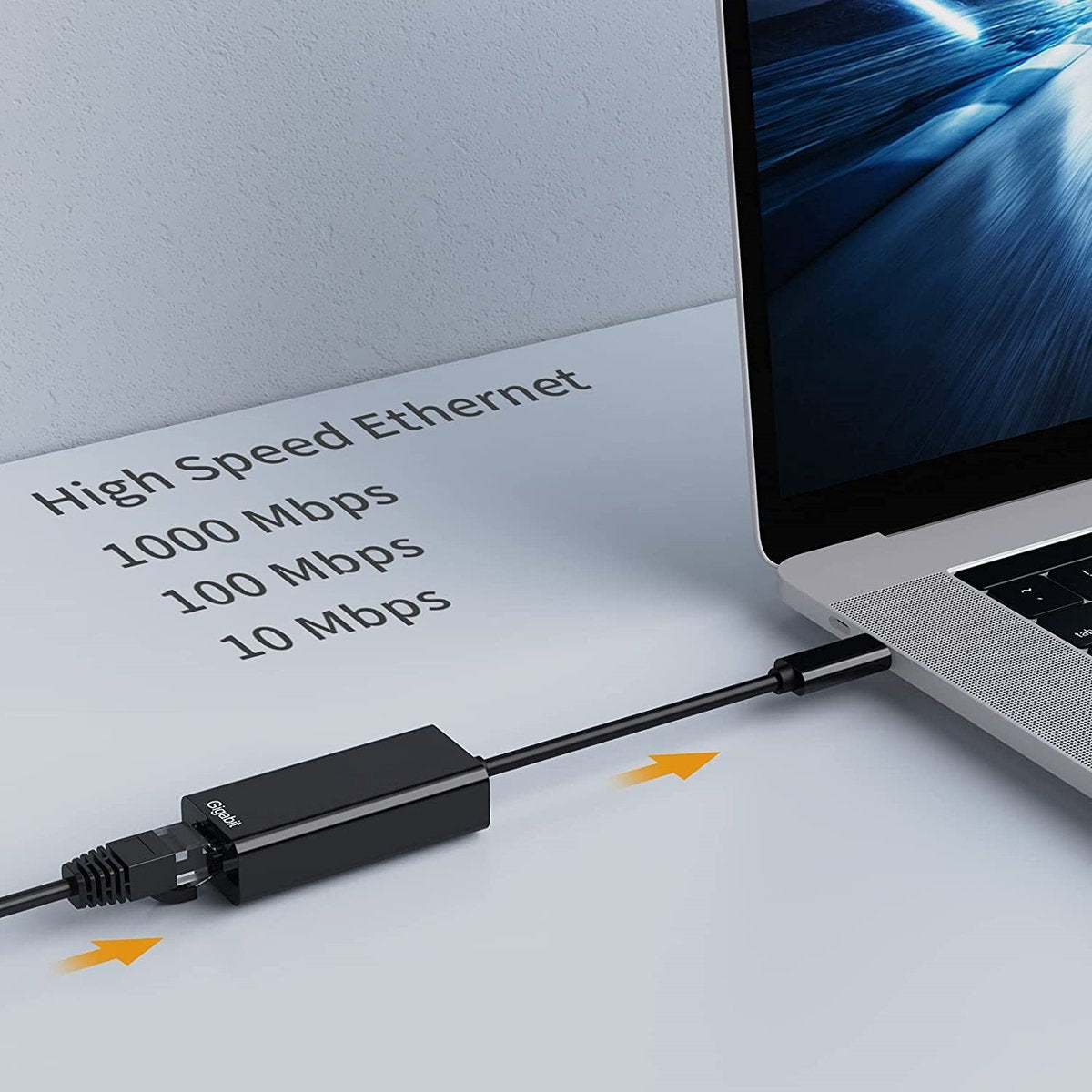 A black Ethernet adapter connected to a laptop. Text on paper reads 'High Speed Ethernet' and speed options.