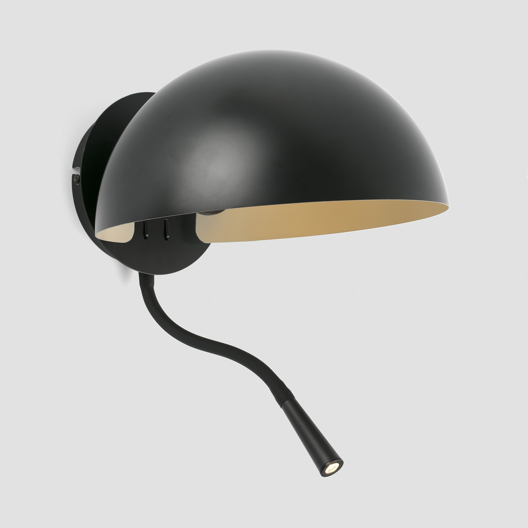 Una lampada da parete nera con un braccio curvo. Ha un paralume a cupola e una piccola luce focalizzata.