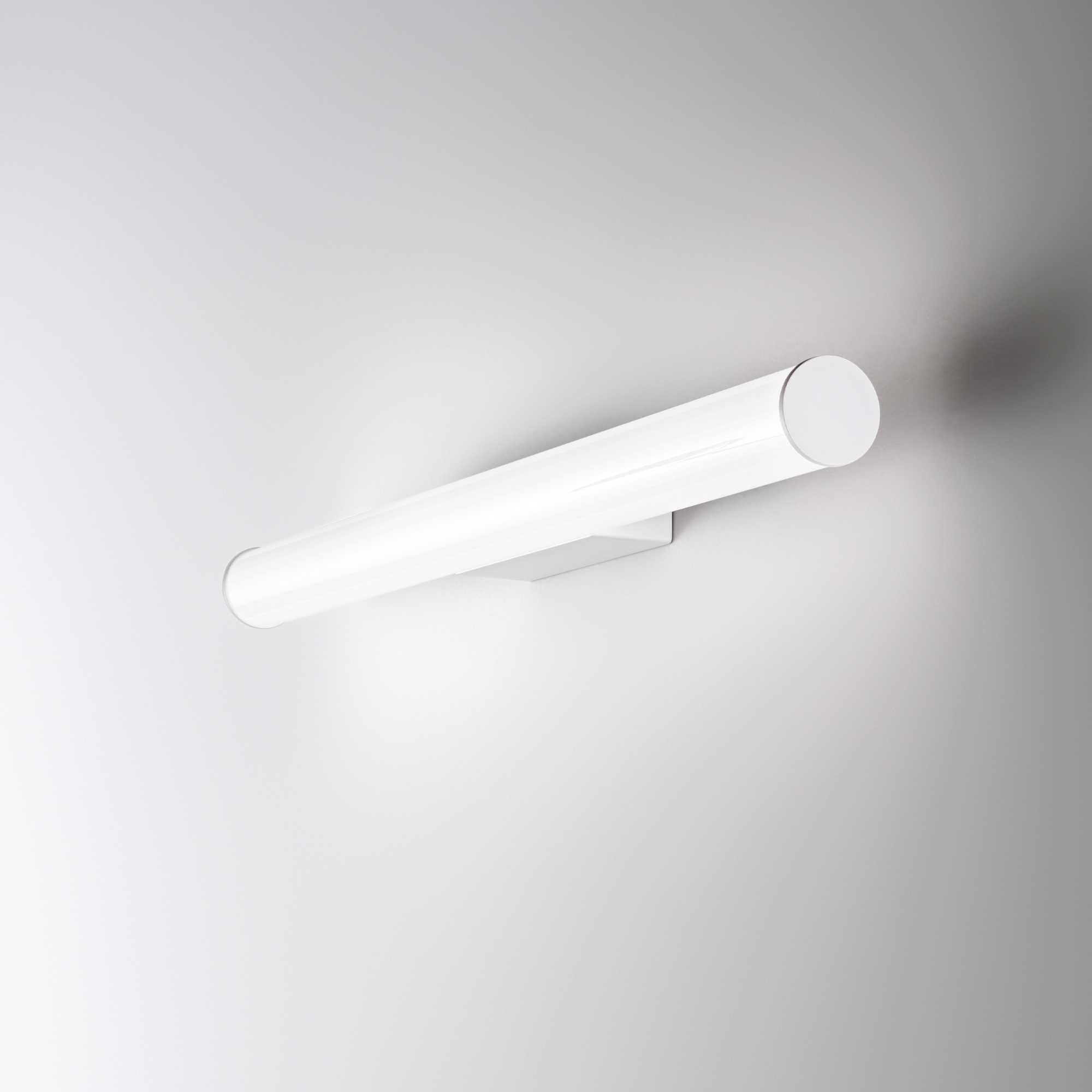 Un apparecchio di illuminazione bianco, cilindrico, montato su una parete bianca. Ha una base rettangolare.