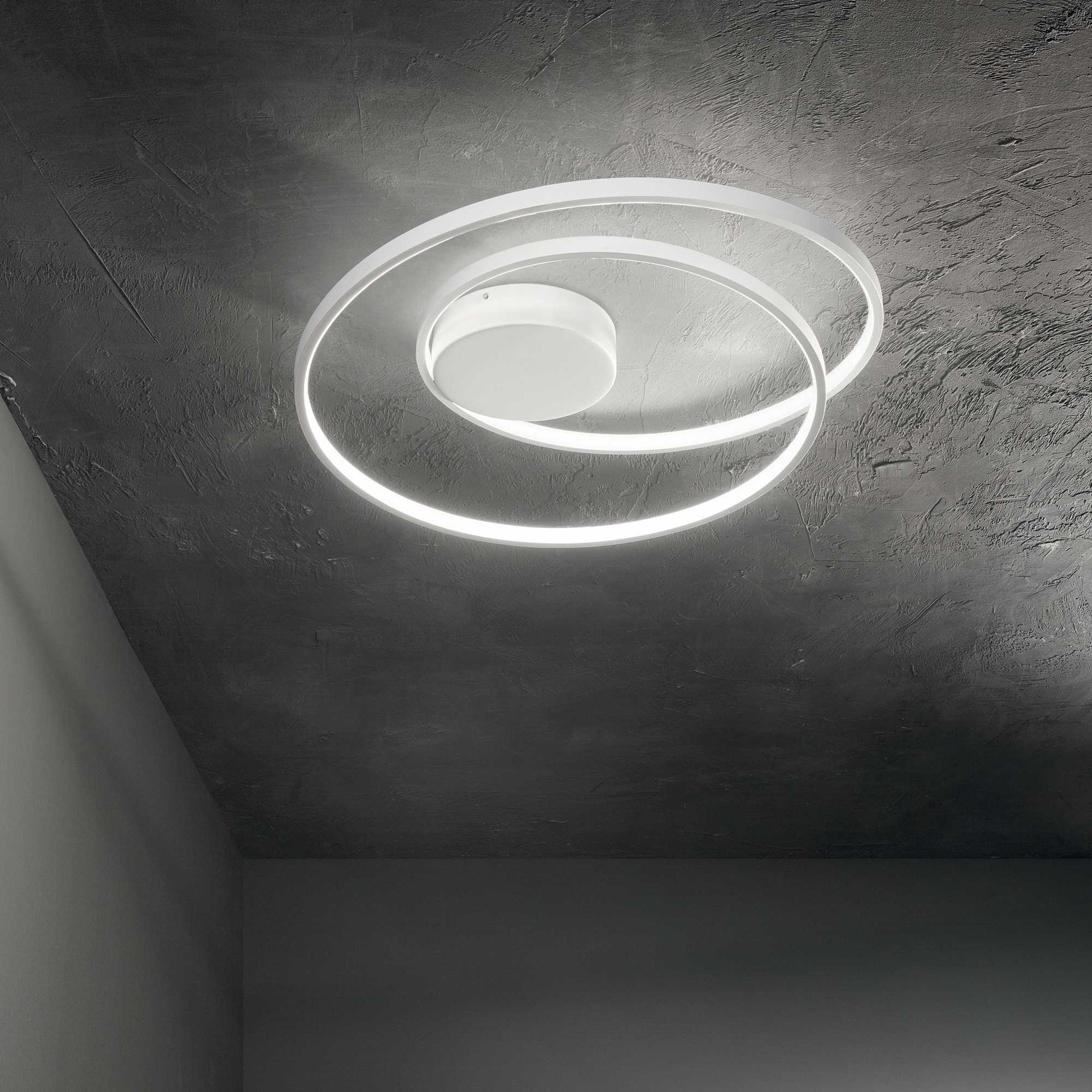 Una moderna plafoniera bianca con design a spirale, su un soffitto grigio strutturato.