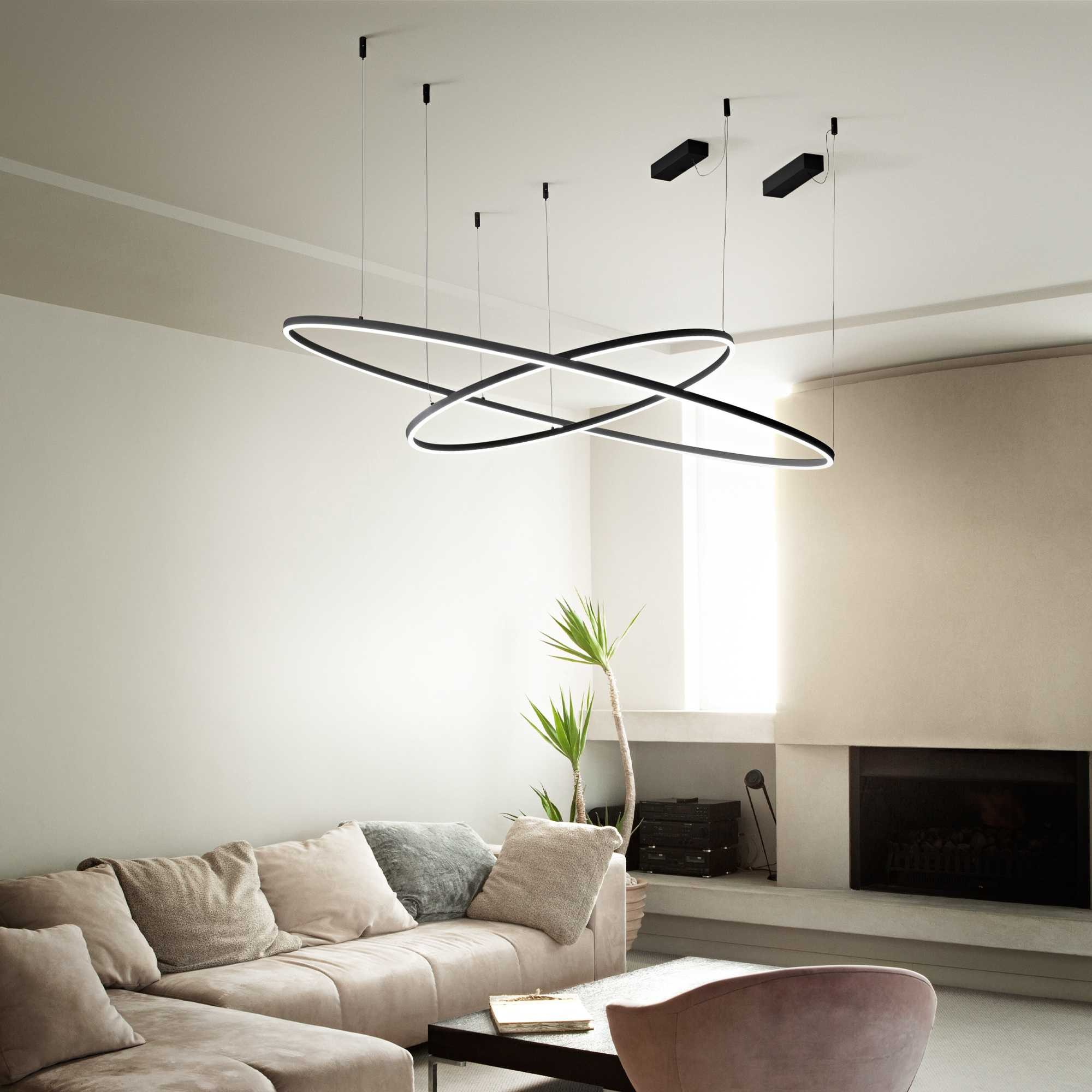 Soggiorno con illuminazione moderna, divano e camino. Luci nere circolari pendono dal soffitto. Toni beige e bianco.
