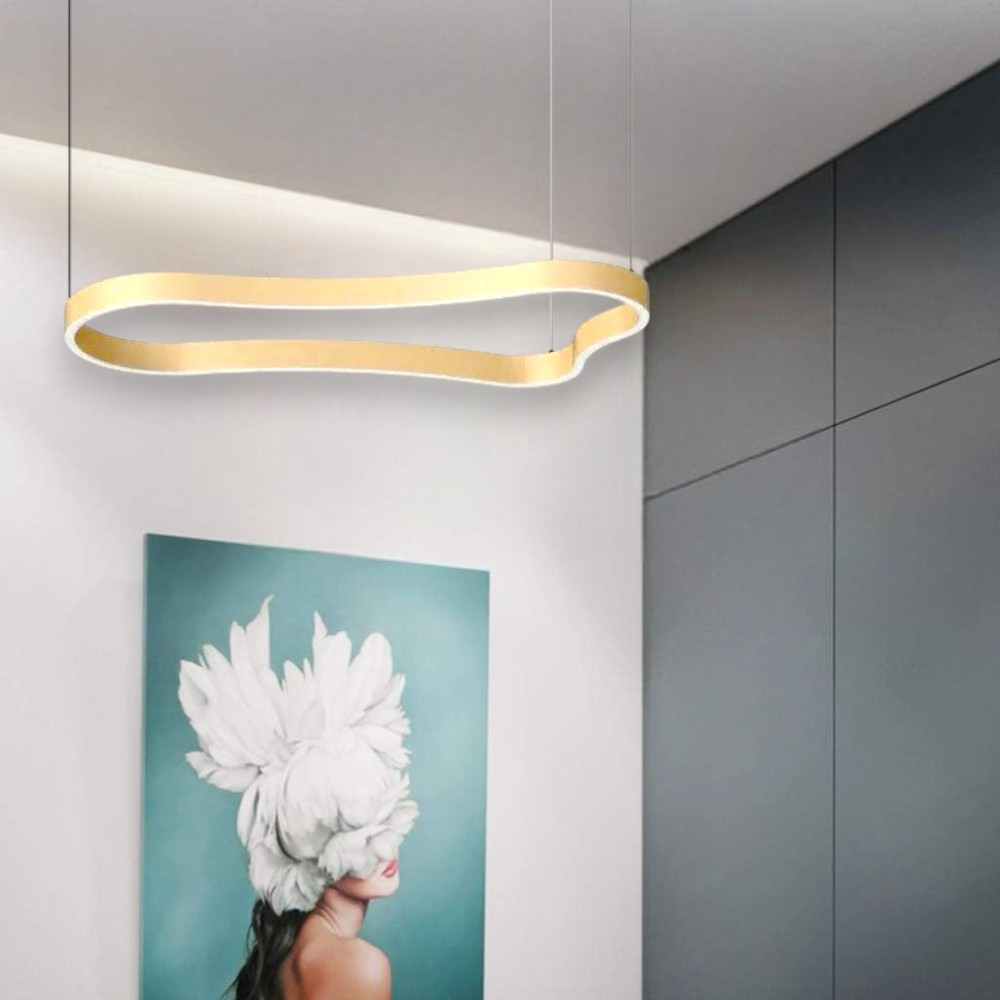 Un interno moderno con un'apparecchio di illuminazione dorato e ondulato. Sotto, un dipinto di una donna con testa di fiore. Parete grigia a destra.