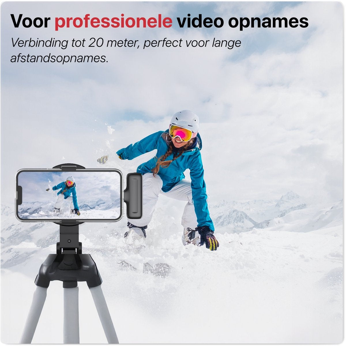 Snowboarder jumps in front of snowy mountains. A phone on a tripod records the action, advertising professional video recording.