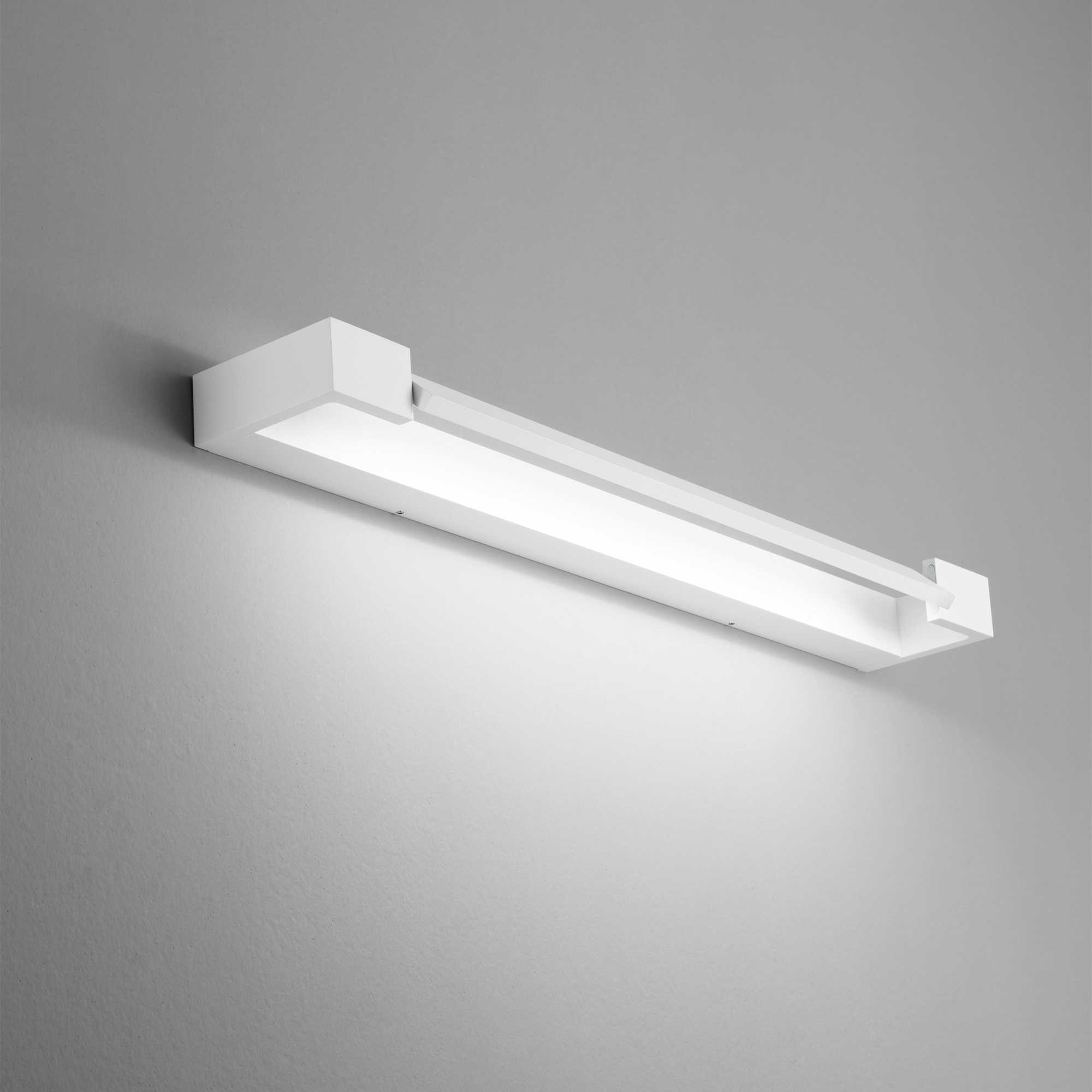 Un apparecchio a parete rettangolare bianco è montato su un muro grigio. La luce è accesa, illumina verso il basso.
