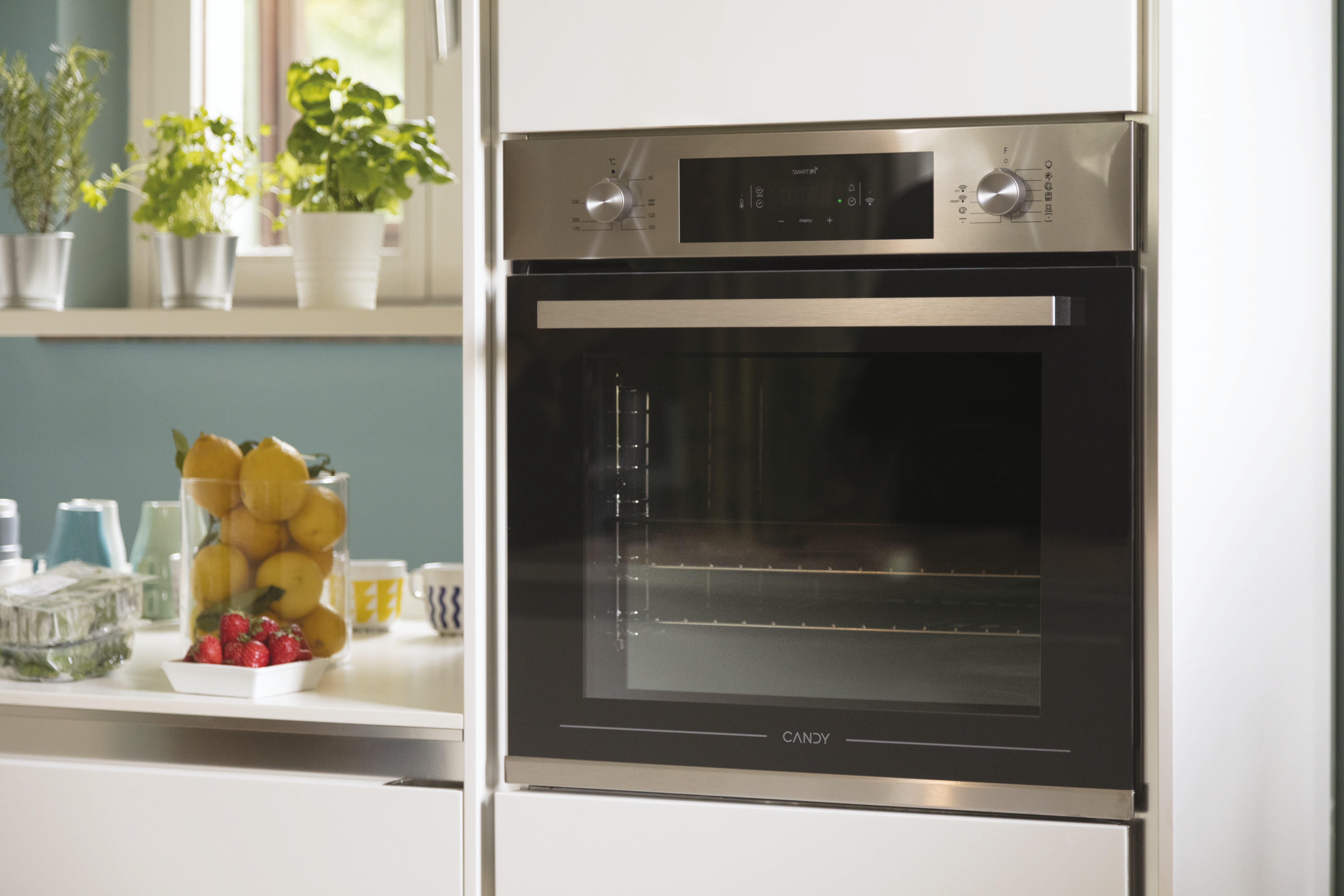 Scena di cucina con forno, limoni, fragole ed erbe. Il forno è in acciaio inossidabile.