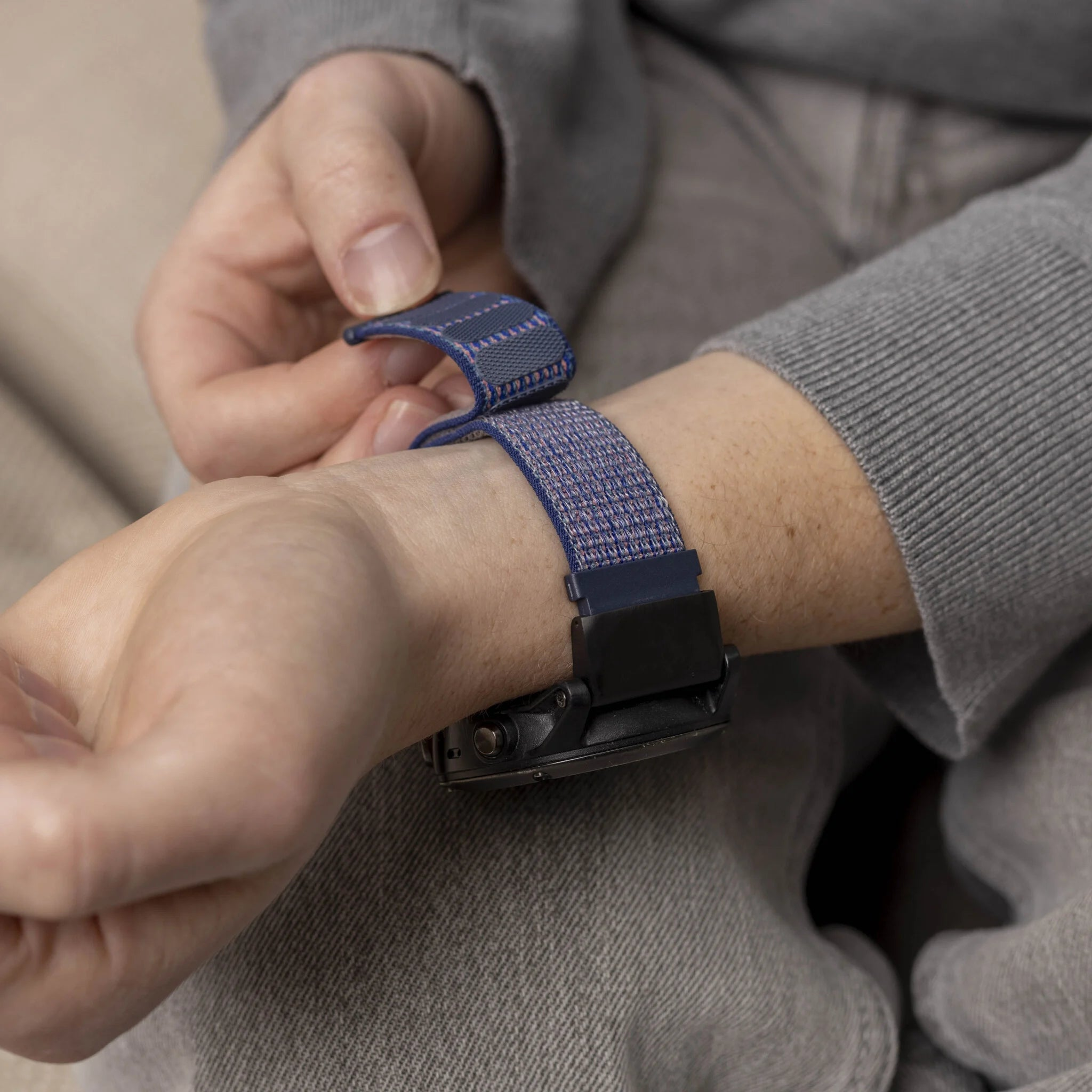 Handgelenk mit Uhr, die befestigt wird. Das Armband hat blaue Muster.