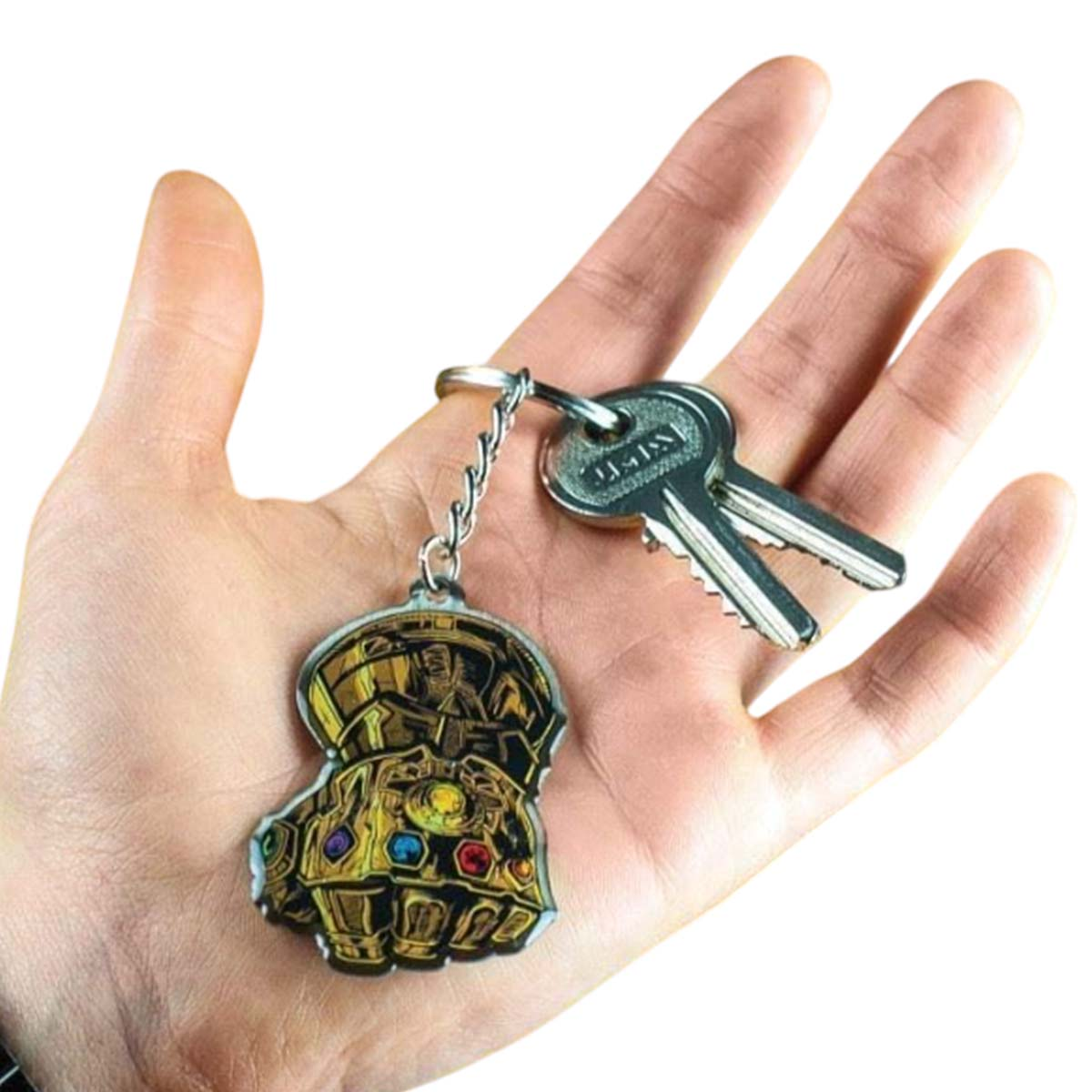 Una mano tiene un portachiavi con un ciondolo del Guanto dell'Infinito e due chiavi. Il guanto è dorato con gemme colorate. Lo sfondo è bianco.