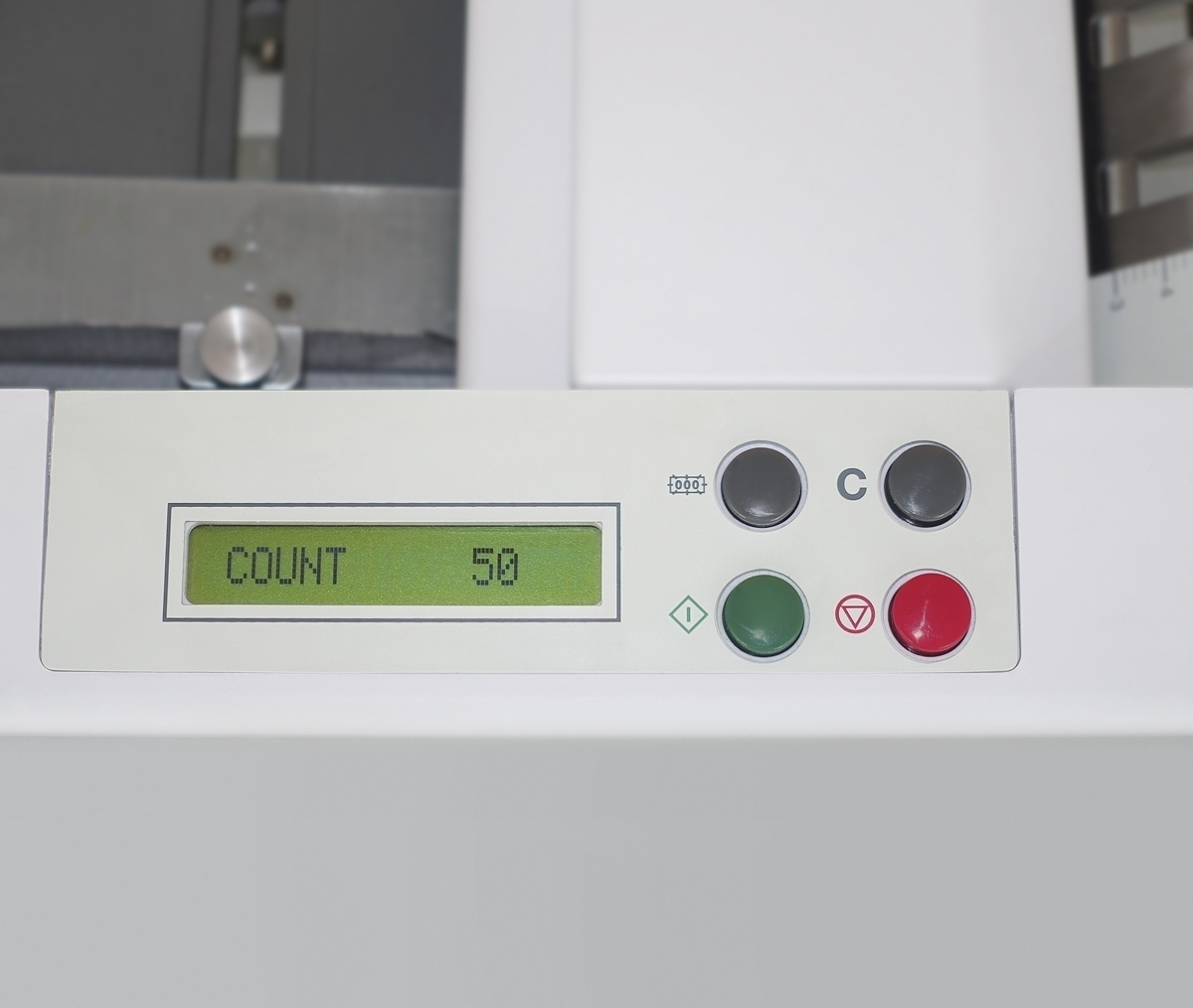 Weißes Maschinenpaneel mit grünem Display, das 'COUNT 50' anzeigt. Knöpfe sind schwarz, grün und rot. Der Hintergrund ist weiß.
