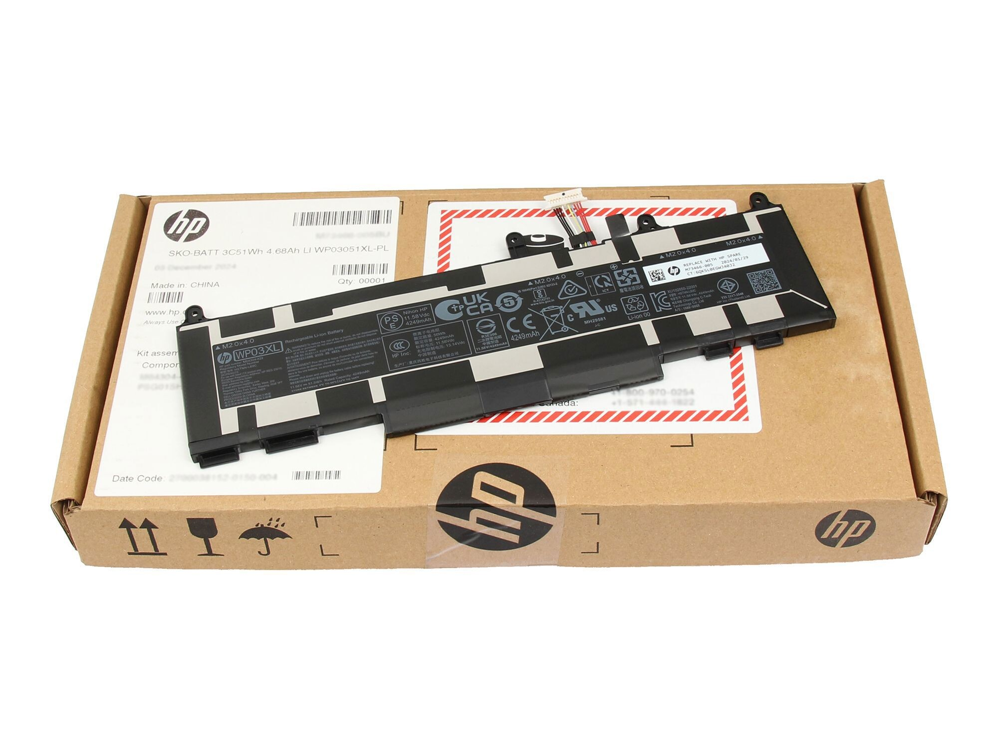 Ein HP-Laptop-Akku in seiner Schachtel. Die Schachtel ist braun mit weißen und roten Markierungen. Batteriedetails sind sichtbar.