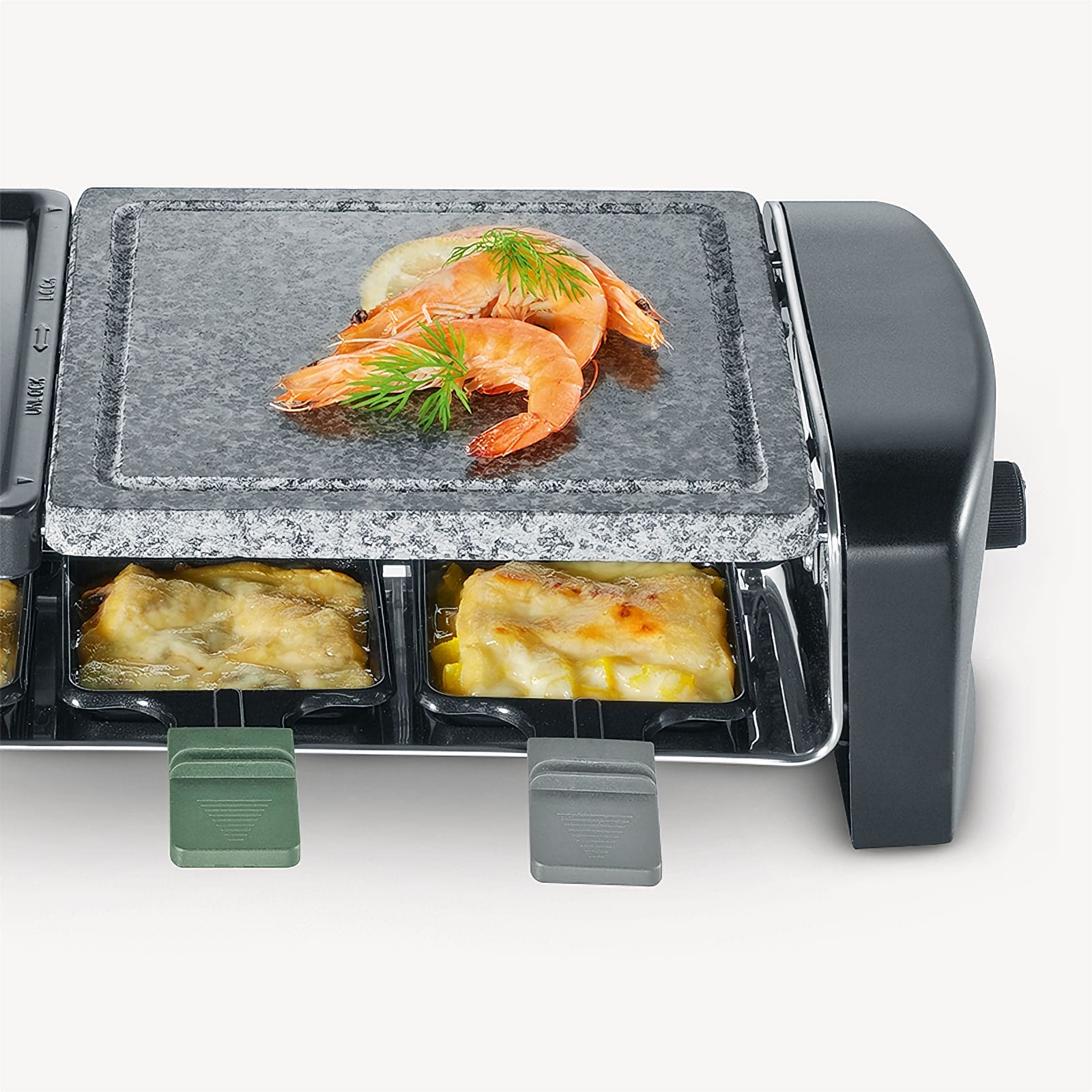 Grill do raclette z krewetkami na górze i serem pod spodem. Czarne i szare urządzenie z tacami do gotowania.