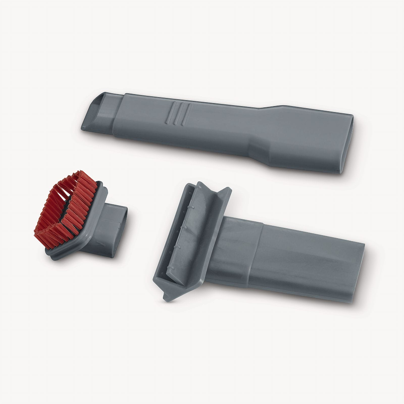 Trzy szare nasadki do odkurzacza na białej powierzchni. Jeden ma czerwoną szczotkę. Jeden jest płaski. Jeden ma skośny koniec.