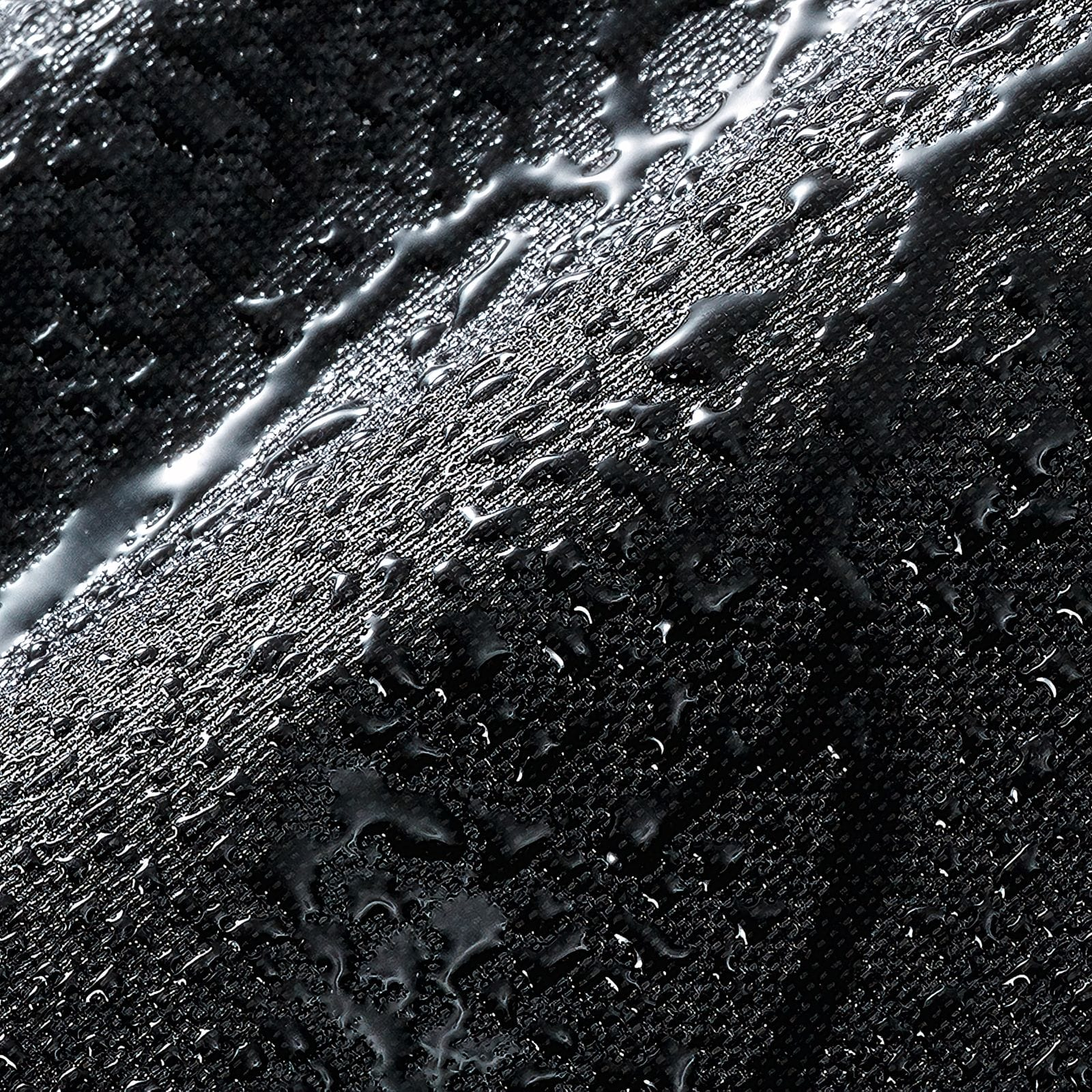 Zbliżenie ciemnej, teksturowanej powierzchni z kroplami wody. Krople odbijają światło, tworząc refleksy na tle.
