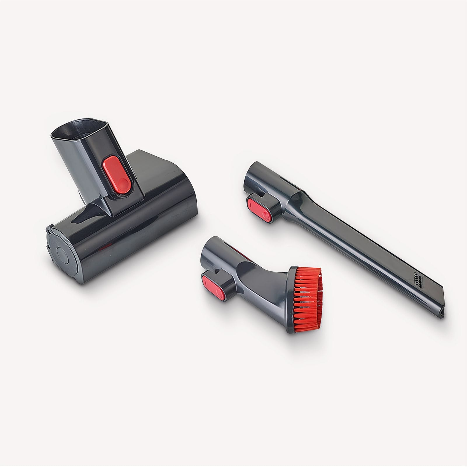 Accessori per aspirapolvere: testina principale, spazzola e bocchetta a lancia. Grigi con bottoni e setole rosse. Sfondo bianco.