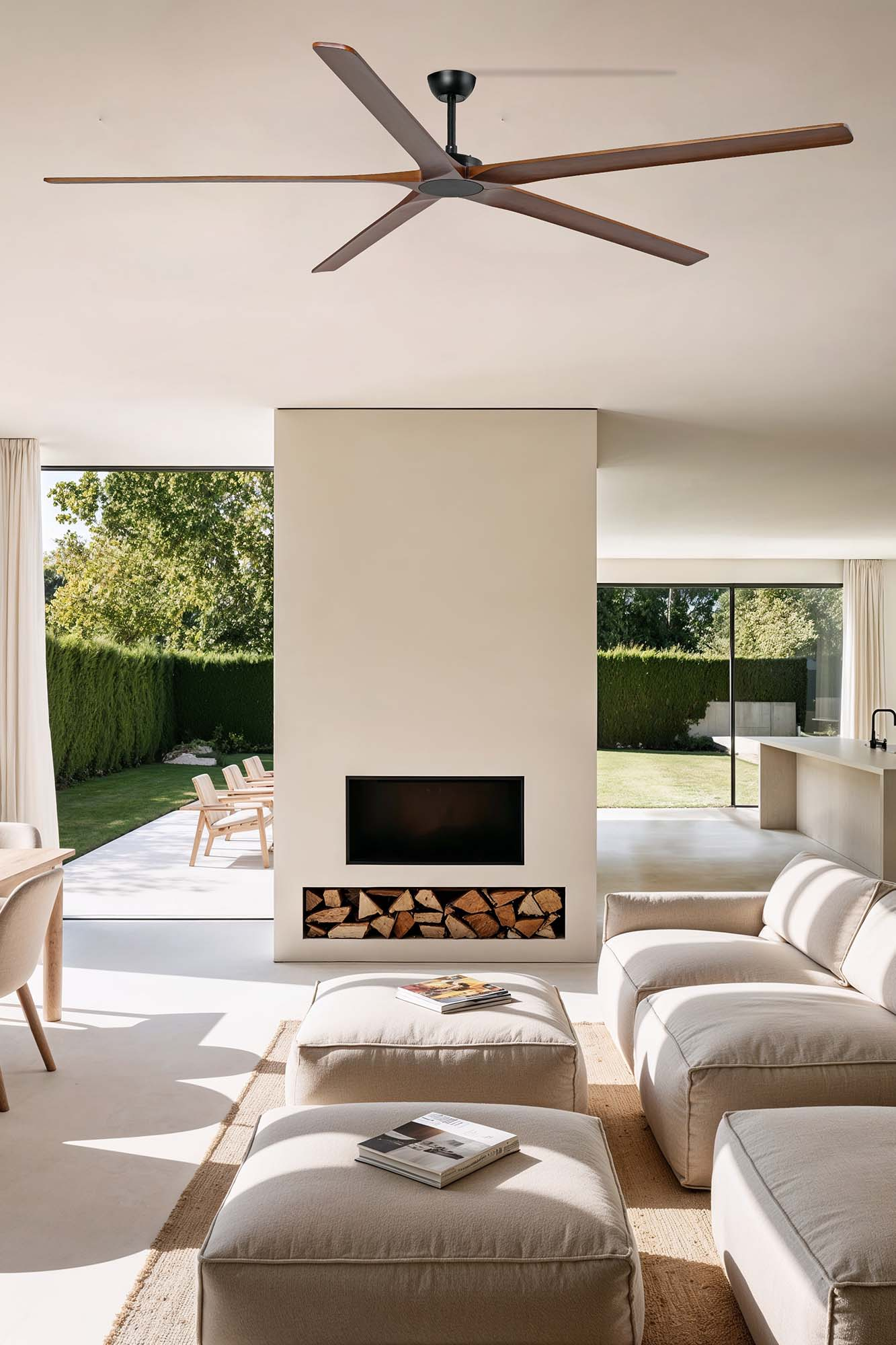 Soggiorno moderno con ventilatore a soffitto. Visibili camino, area salotto e vista esterna attraverso ampie finestre.