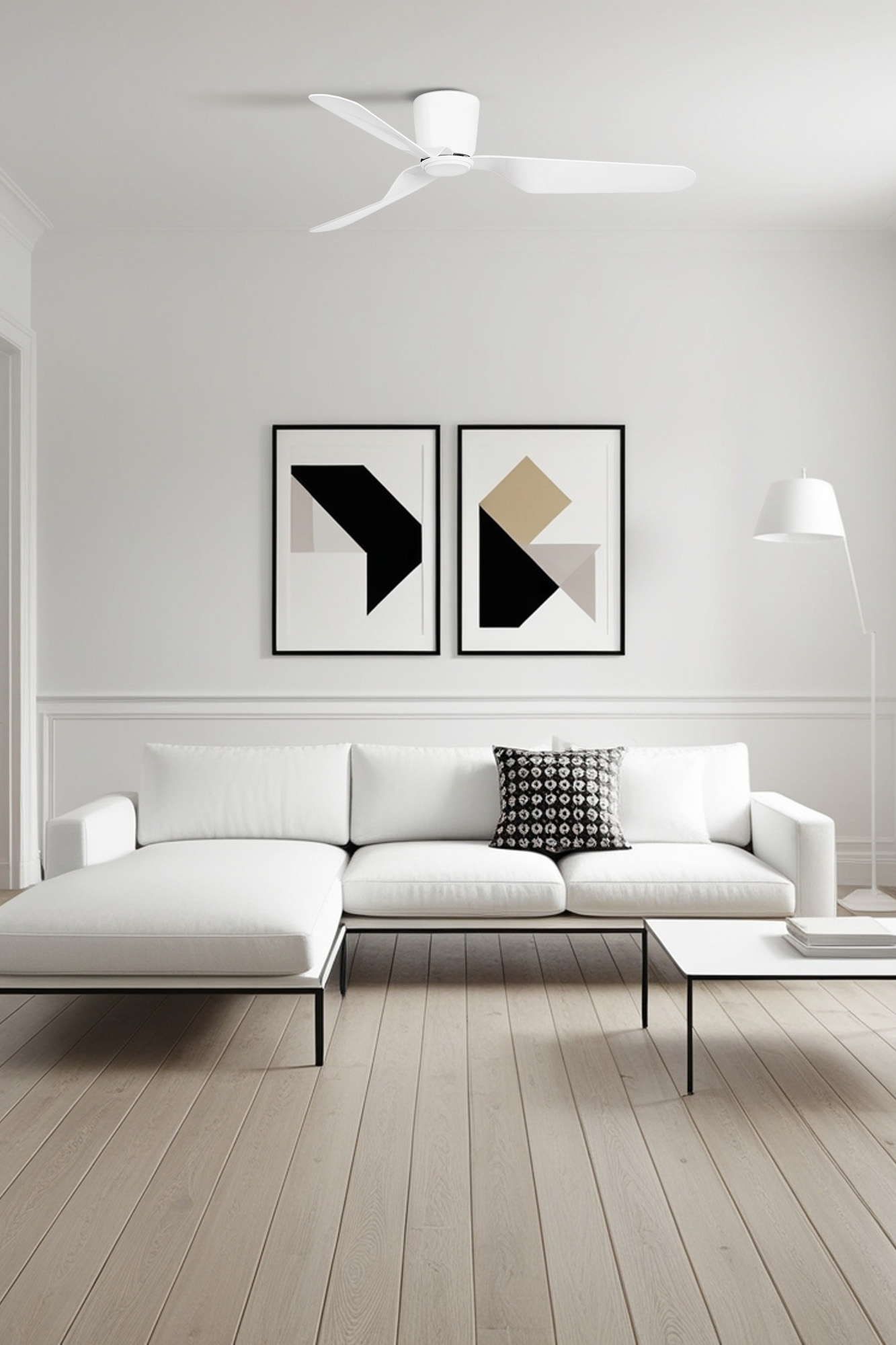 Un soggiorno moderno con un divano bianco, due opere d'arte incorniciate, un tavolino e un ventilatore a soffitto. Pavimento in legno.