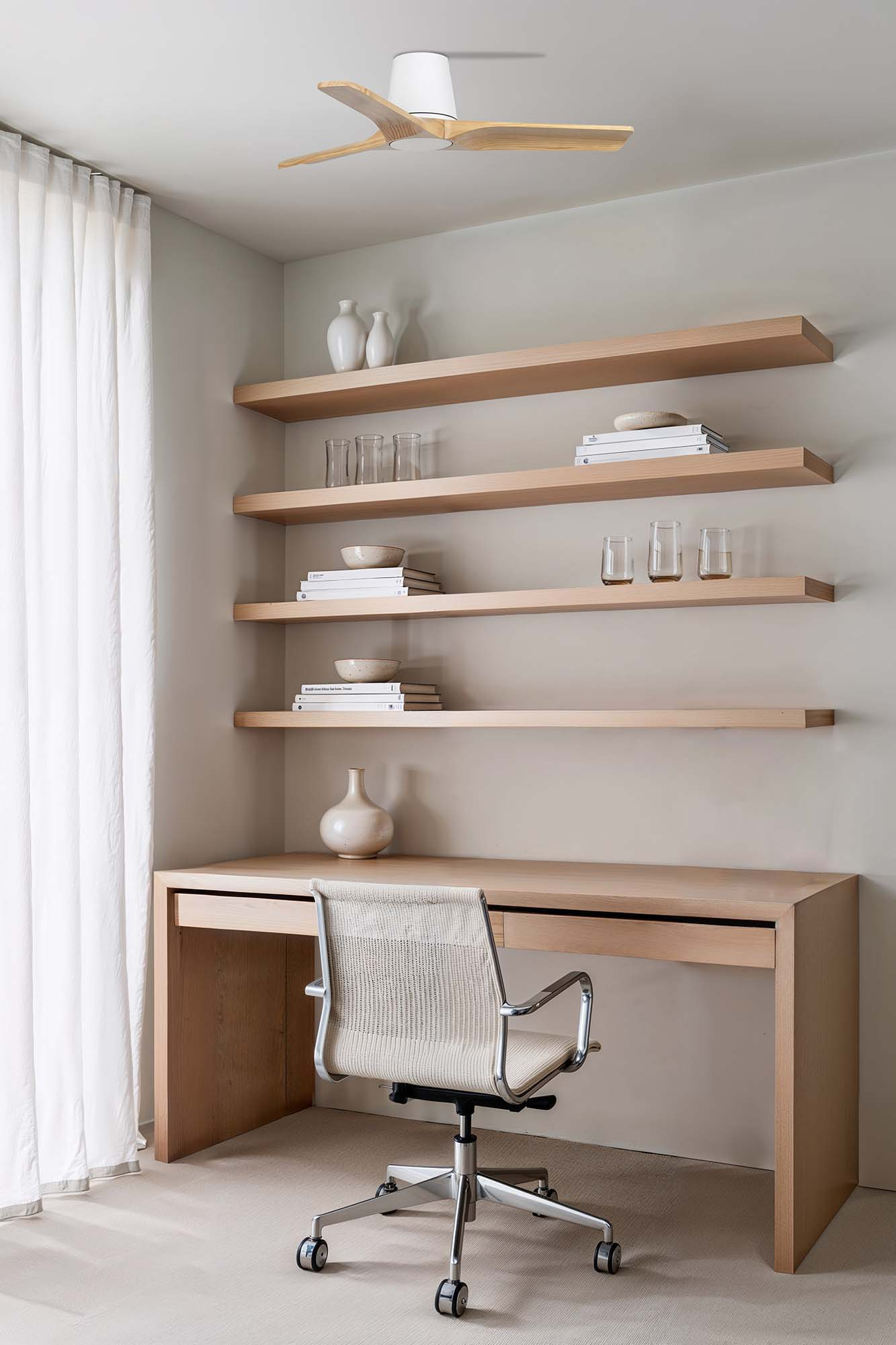 Ein modernes Büro mit Schreibtisch, Stuhl, Regalen mit Dekoration und Deckenventilator. Links ein weißer Vorhang.