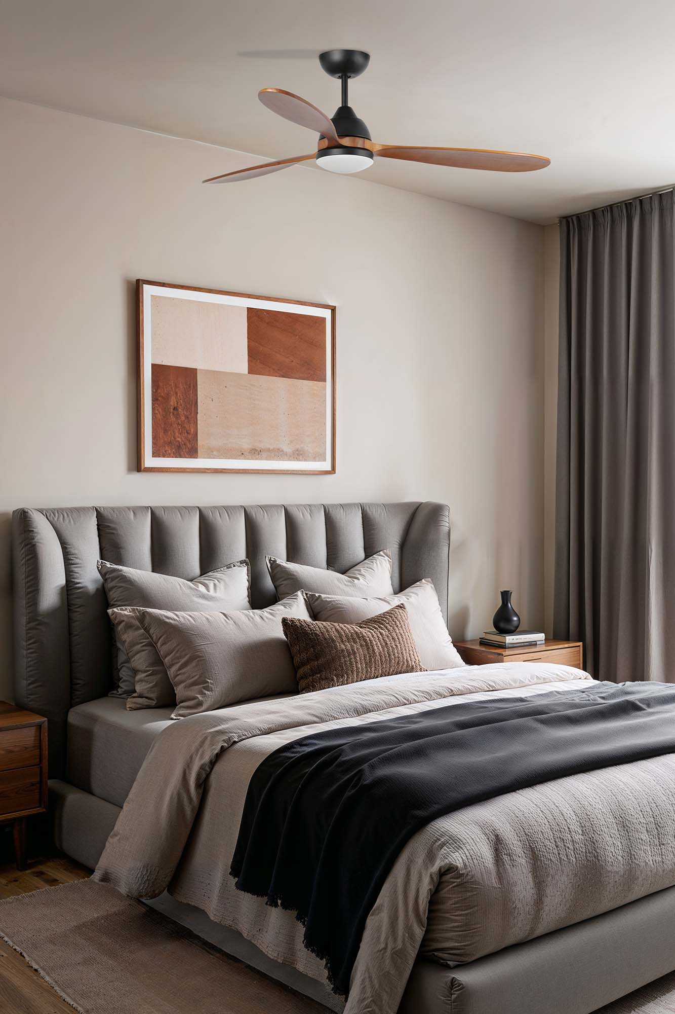 Schlafzimmer mit Bett, Kunst, Deckenventilator. Bett hat graues Kopfteil, Kissen, Decke. Kunst hat Braun- und Beigetöne. Ventilator hat Holzblätter.