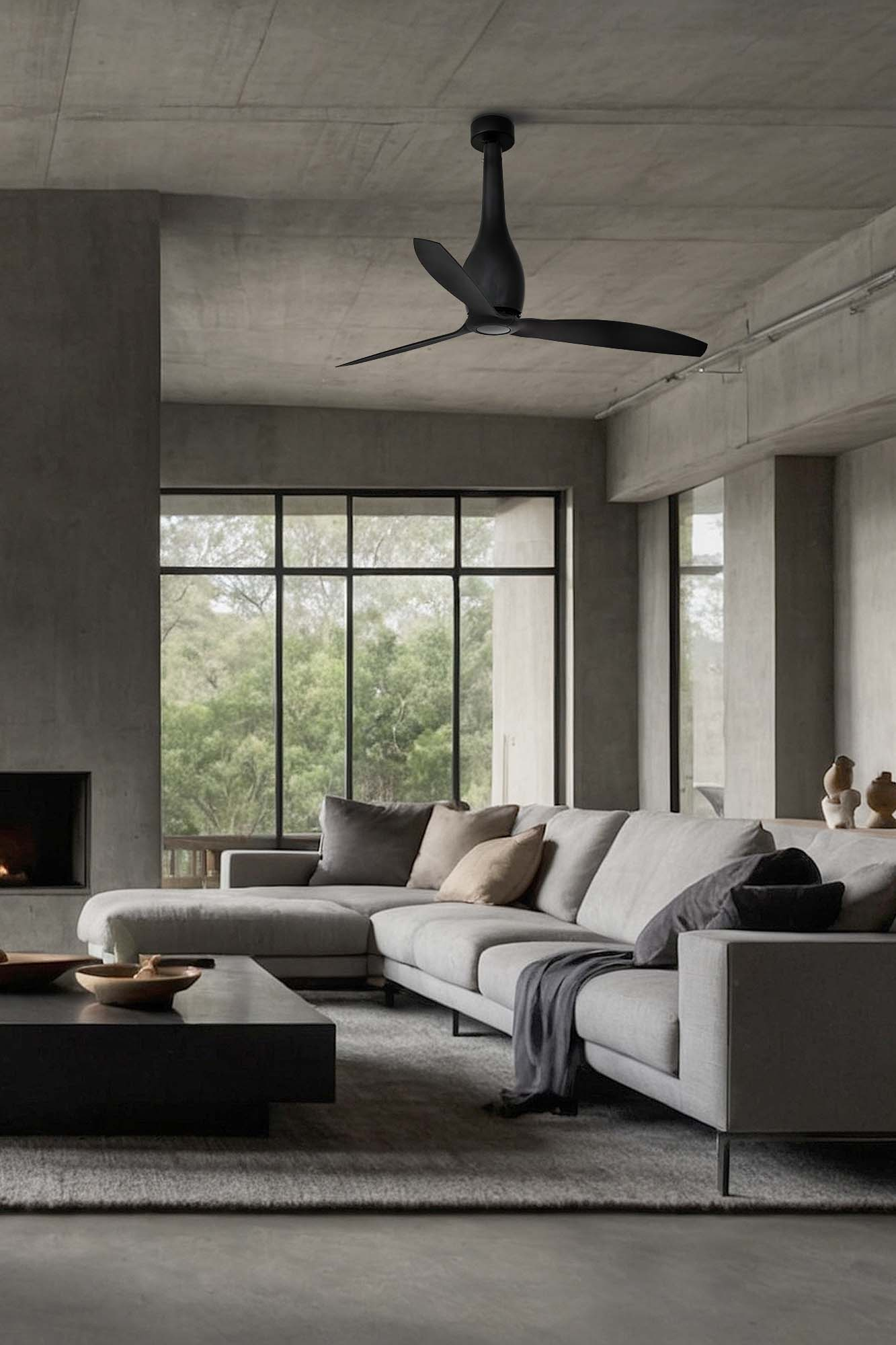 Ein modernes Wohnzimmer mit grauem Sofa, schwarzem Deckenventilator, großem Fenster mit Bäumen und dunklem Couchtisch.