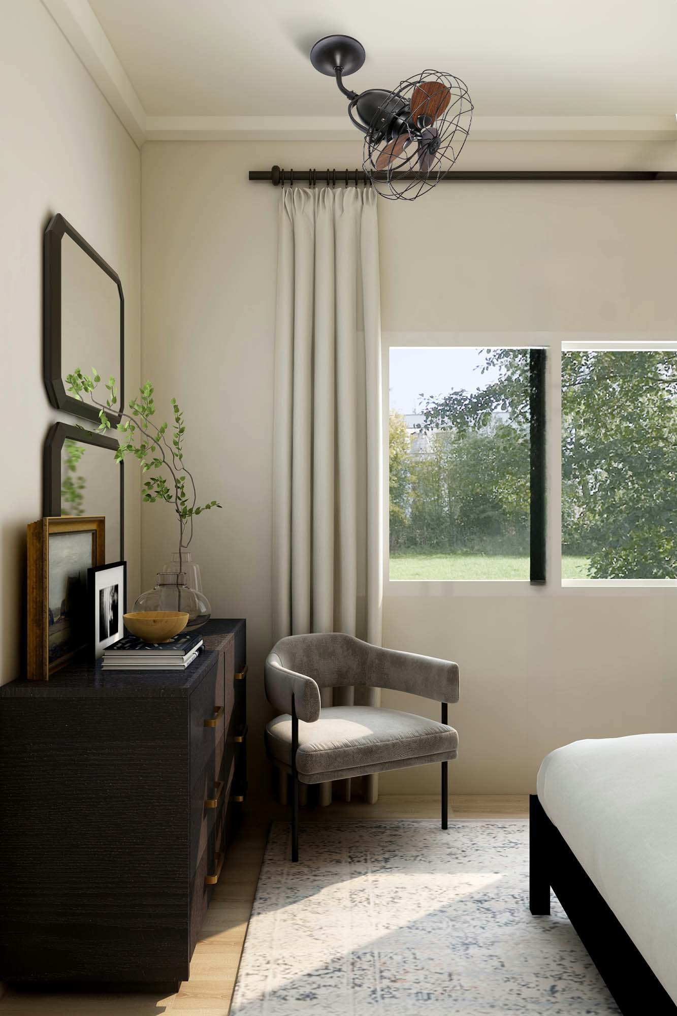 Camera da letto con cassettiera scura, sedia grigia e finestra con vista sugli alberi. Ventilatore a soffitto montato.