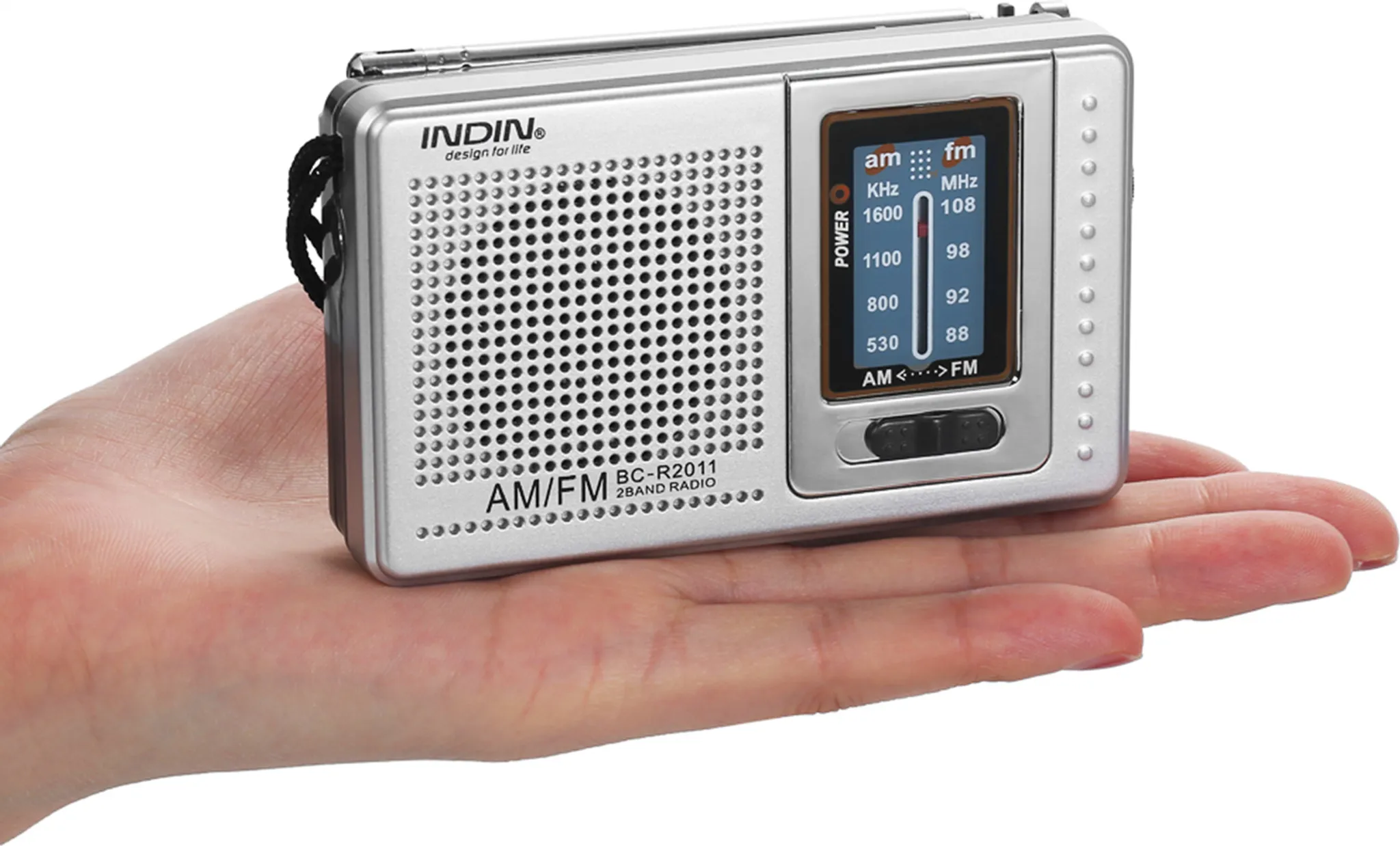 Ein silbernes AM/FM-Radio, das in einer Hand gehalten wird. Es zeigt Frequenznummern und hat einen schwarzen Riemen.