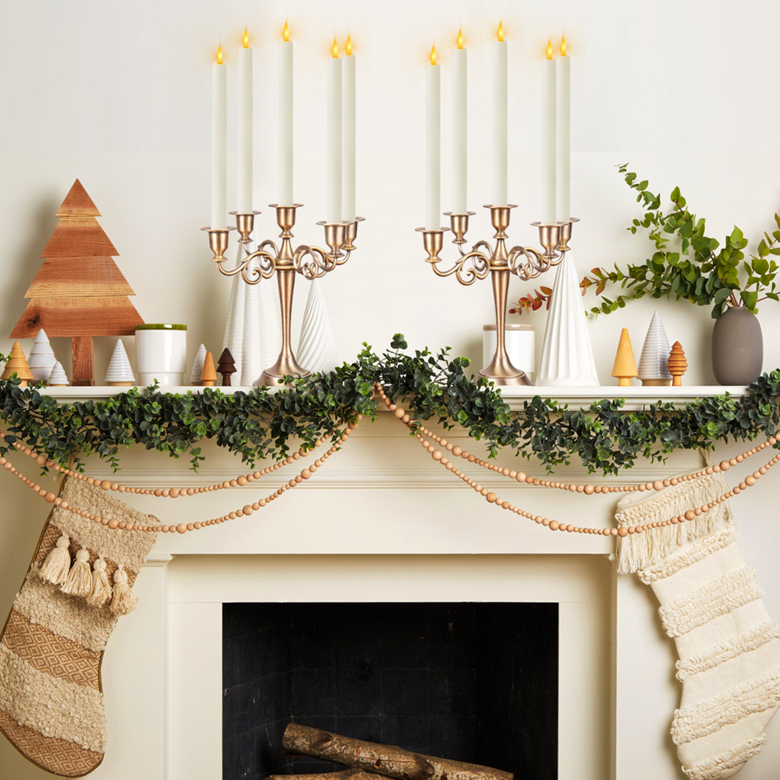Weihnachtlich dekorierter Kamin mit Kerzen, Girlande, Holzperlen, Strümpfen und dekorativen Bäumen.