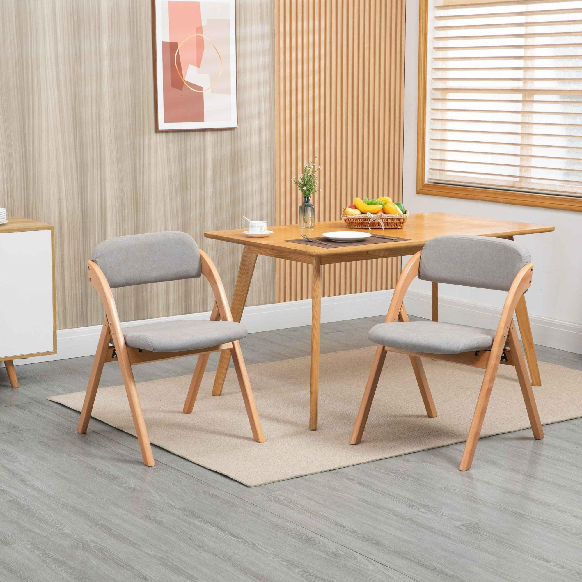 Ein Esszimmer mit Holztisch, zwei grauen Stühlen und einem Obstkorb. Hellgrauer Boden und beiger Teppich.