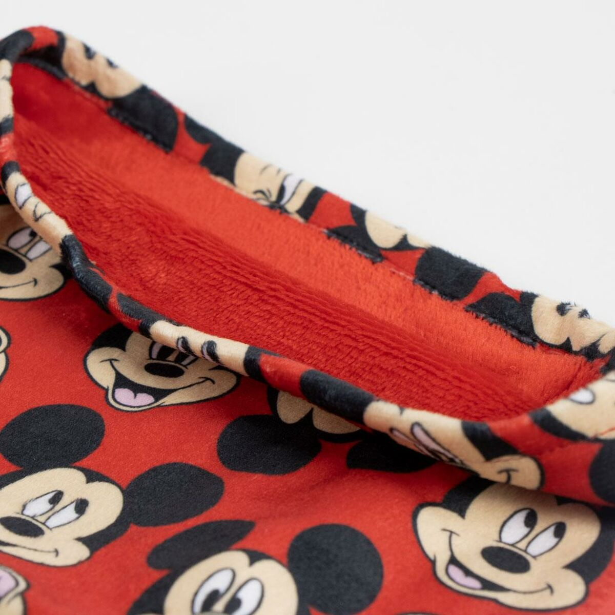 Nahaufnahme eines roten Stoffes mit Mickey Mouse Gesichtern. Der Stoff hat ein rotes Innenfutter und einen beigen Rand mit Mickys Gesicht.