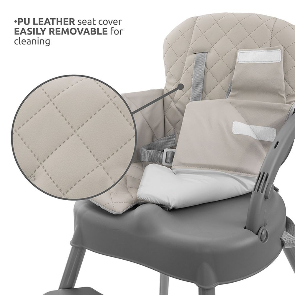 Una silla alta para bebés con asiento de cuero PU beige y estructura gris. Cuenta con respaldo acolchado, cinturones de seguridad y funda extraíble.
