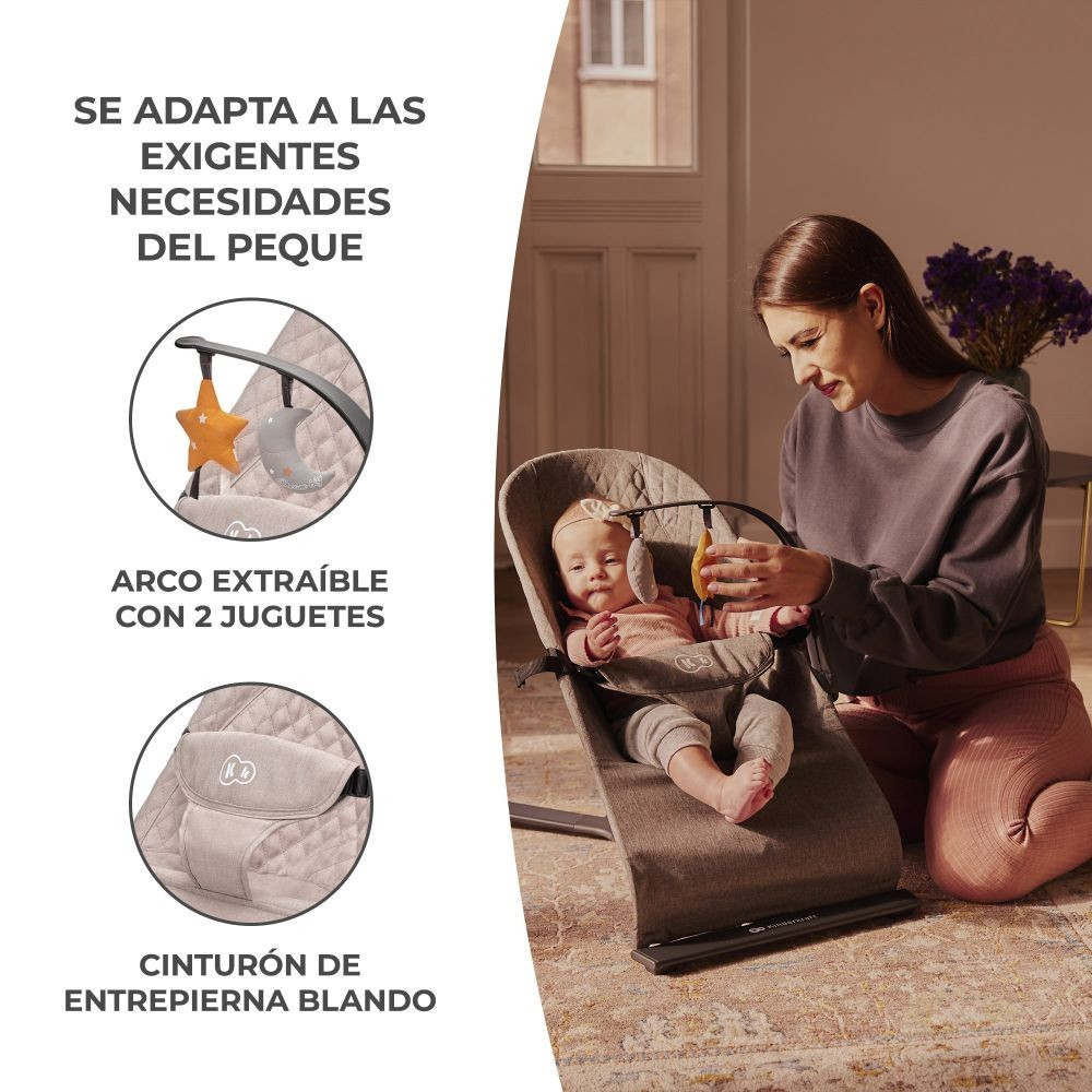 Madre y bebé en un balancín. La madre ajusta un juguete. El balancín tiene un juguete de estrella y luna. Texto en español presente.