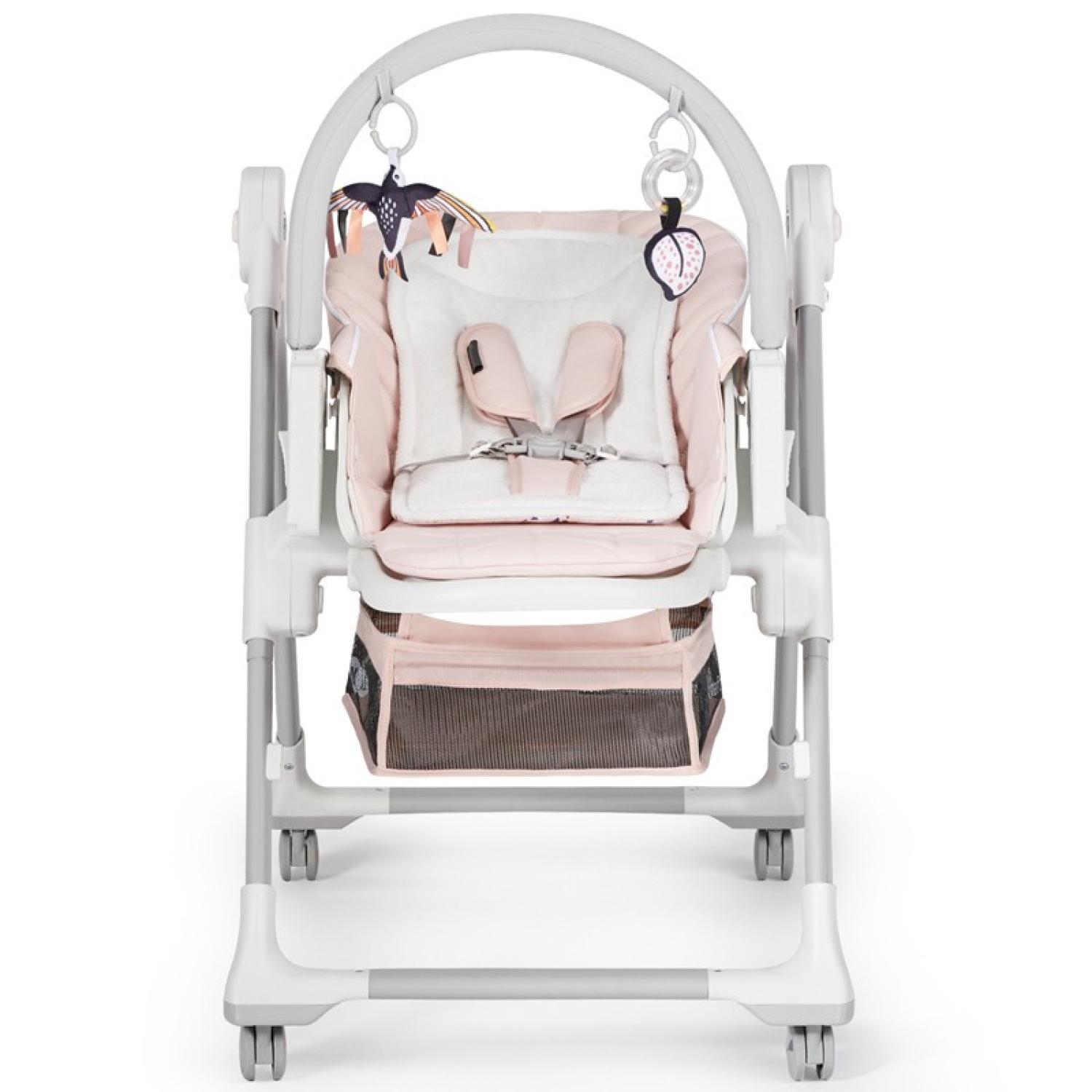 Ein Babyhochstuhl, rosa Sitz, Spielzeug darüber hängen. Der Stuhl hat einen Aufbewahrungskorb und Räder.
