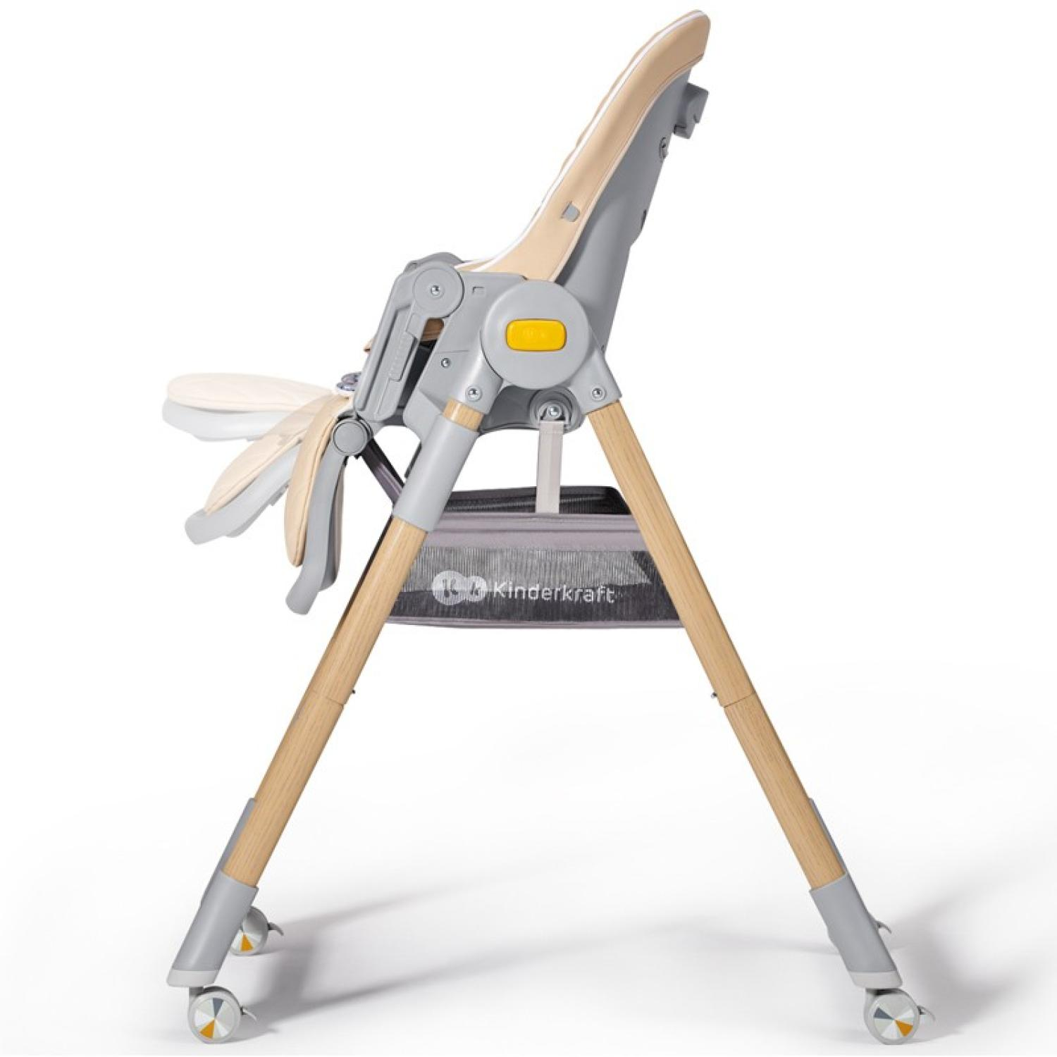 Ein Hochstuhl, beige und grau, wird von der Seite gezeigt. Er hat Holzbeine, ein Tablett und Räder. Der Stuhl ist leer.