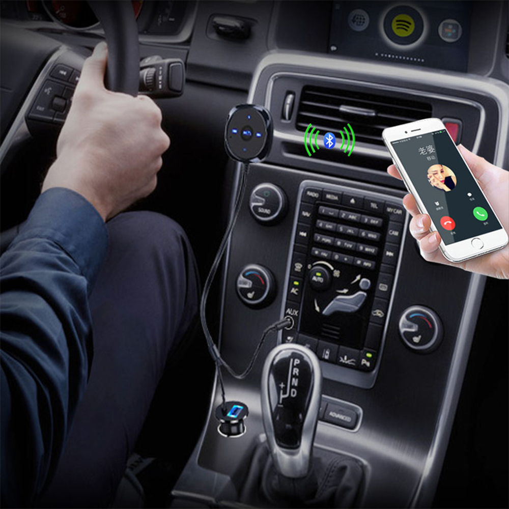Eine Person im Auto hält ein Telefon mit Anrufbildschirm. Bluetooth-Gerät und Fahrzeugsteuerung sichtbar.