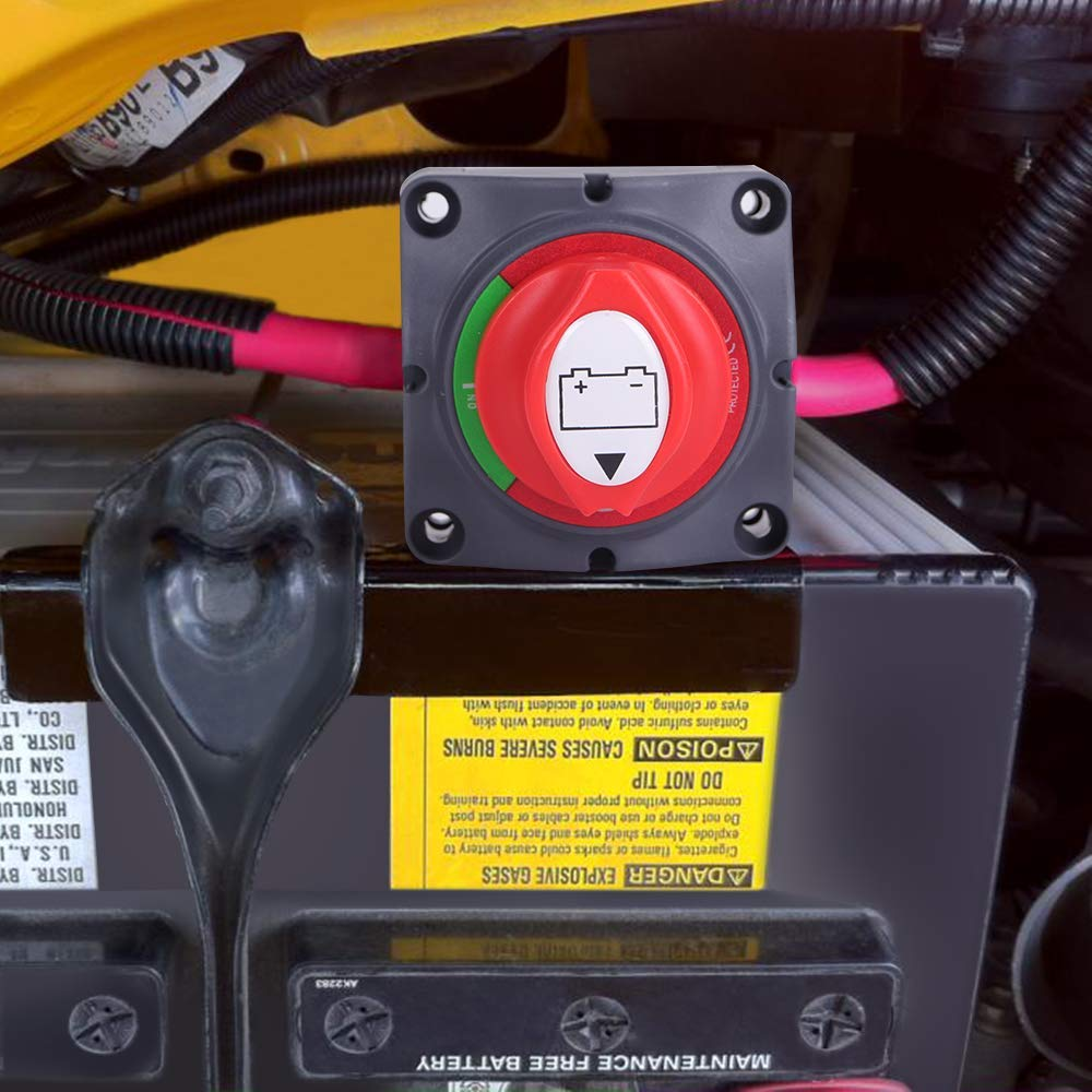 Ein roter und grüner Batterietrennschalter ist auf einer schwarzen Oberfläche montiert. Ein gelber Aufkleber mit Warnhinweisen ist sichtbar.