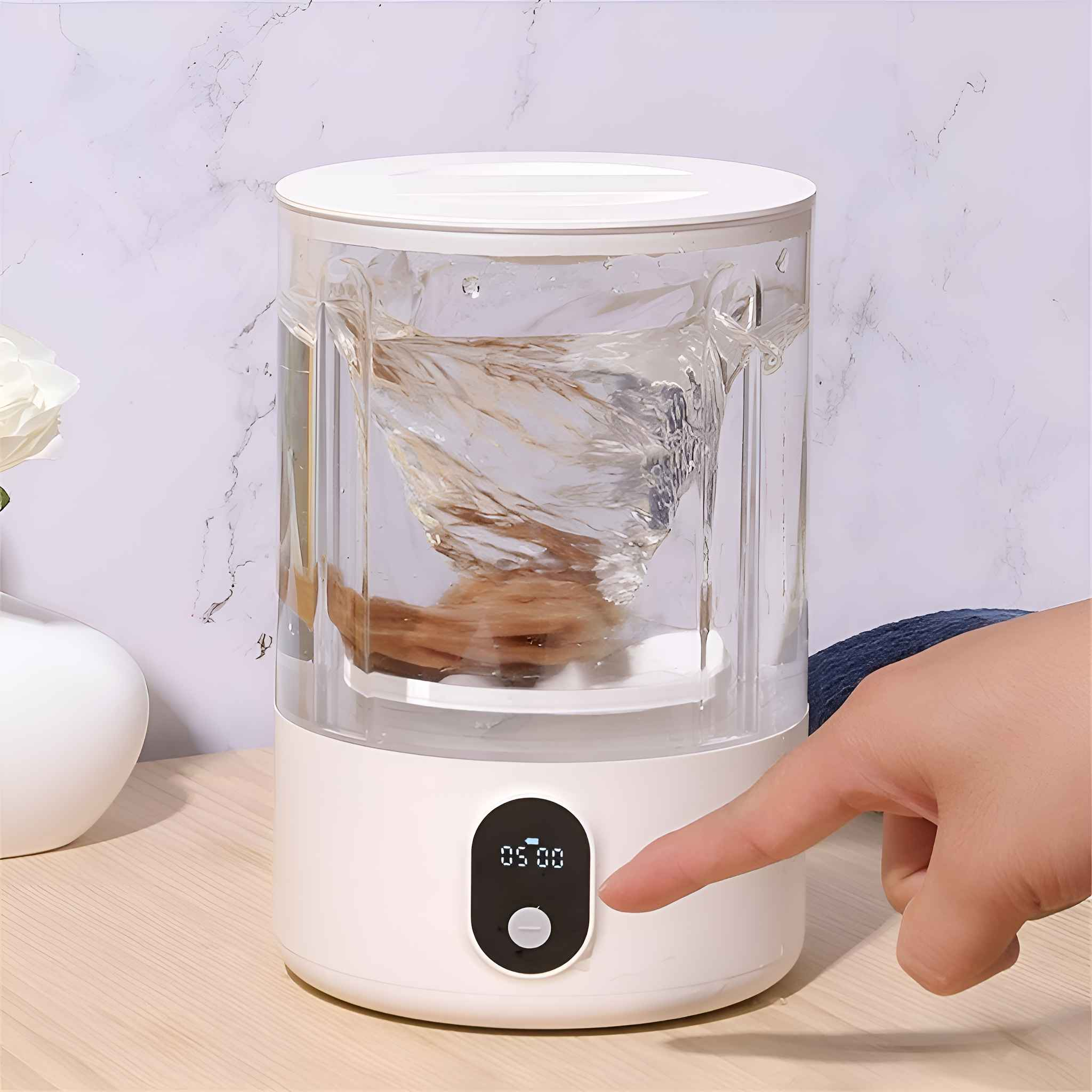 Ein weißer Wasserreiniger mit wirbelndem Wasser im Inneren, eine Hand drückt die Taste. Marmorhintergrund.