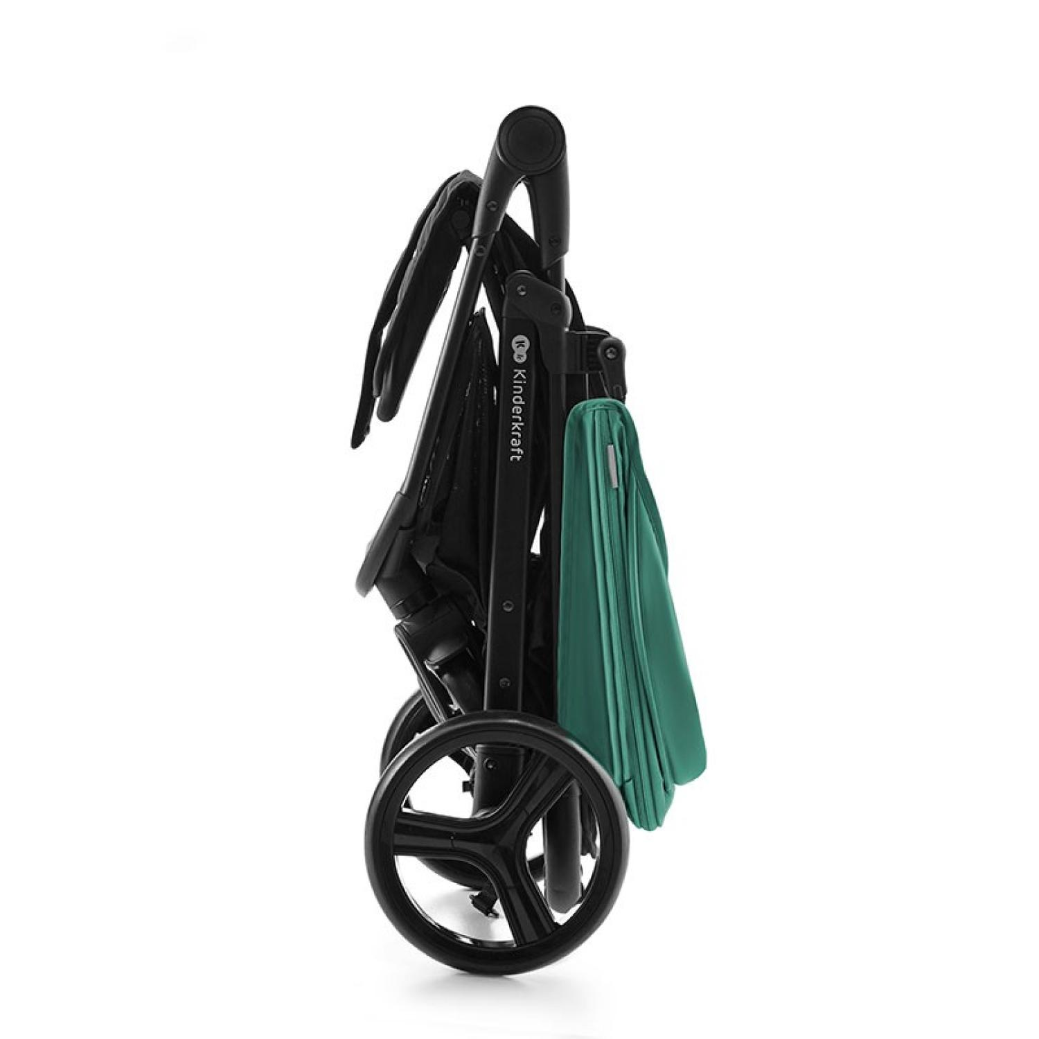Cochecito negro plegado con tela verde azulado, vista lateral. Cuenta con ruedas, manillar y el logotipo de Kinderkraft. Sobre fondo blanco.
