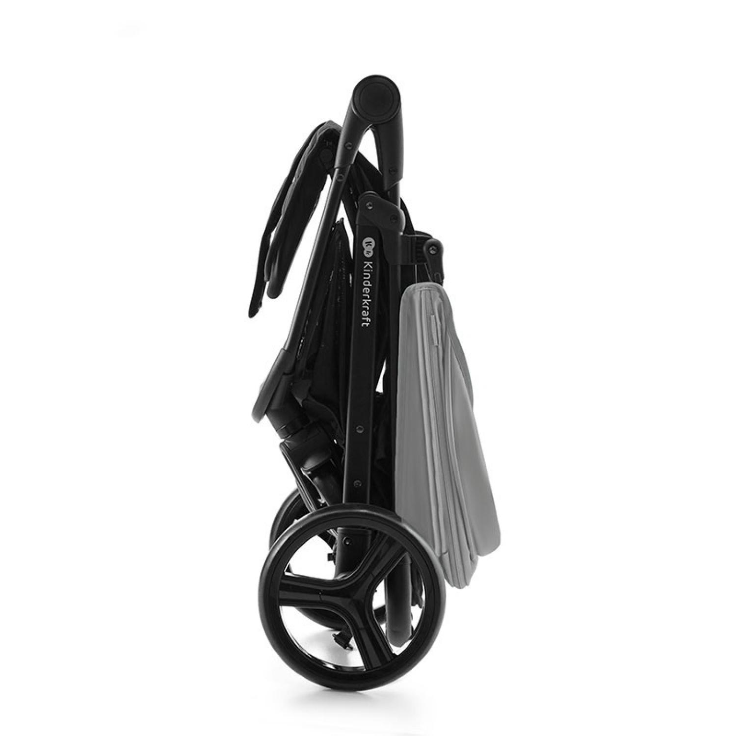 Un cochecito negro y gris plegado, vista lateral. Tiene cuatro ruedas, un asa y un elemento de tela gris. El fondo es blanco.