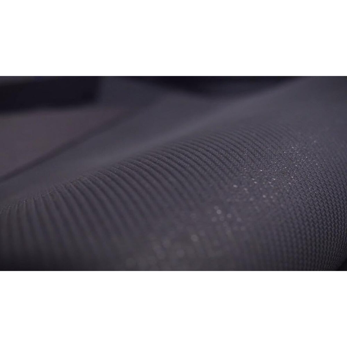 Gros plan sur un tissu côtelé gris foncé. Détails de la texture visibles, avec de subtils reflets de lumière sur la surface. Le tissu semble drapé.