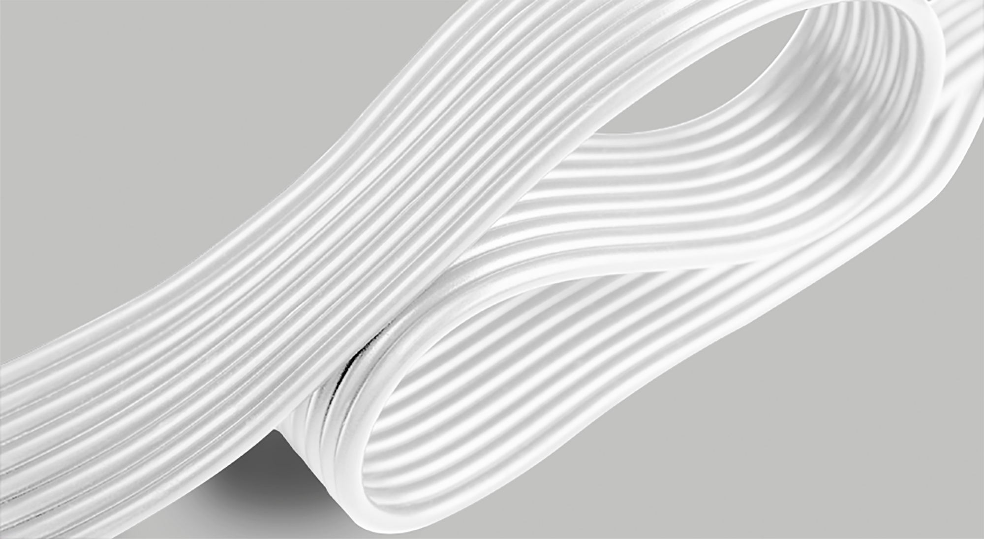 Material blanco y acanalado curva sobre fondo gris. El material parece plegado. Los detalles están bien definidos.