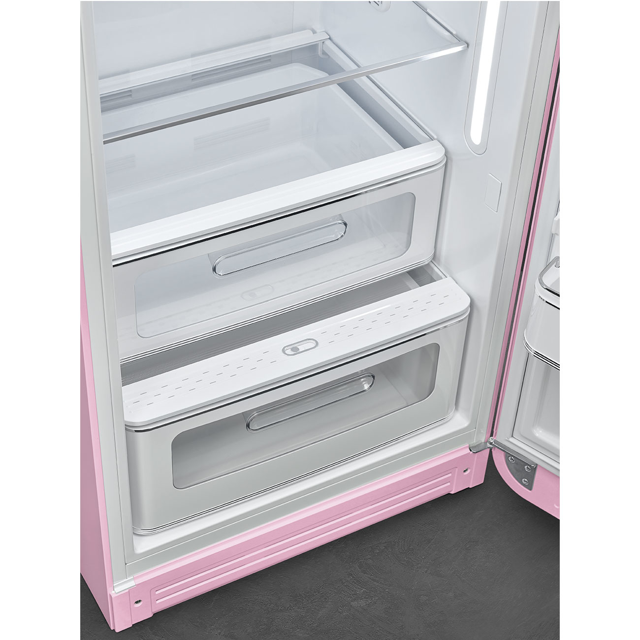 Interno del frigorifero rosa. Sono visibili due cassetti, insieme a ripiani trasparenti. La porta è aperta.